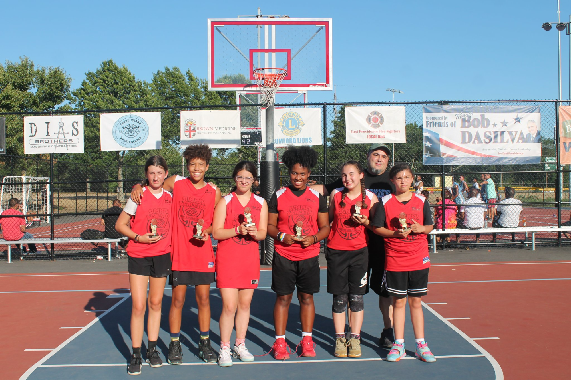 a group of people standing on a track with a basketball hoop in the background