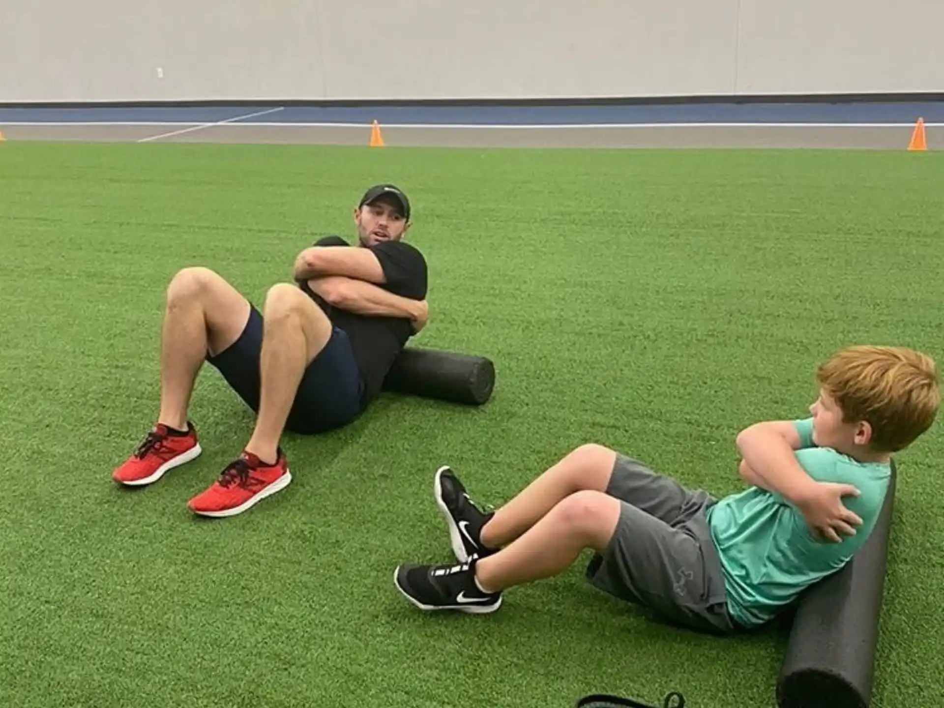 a man and a boy sitting on a bench in a gym
