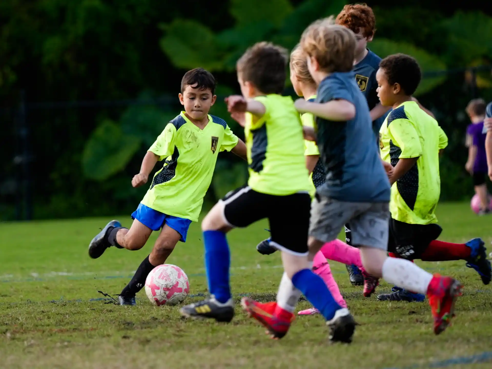 a group of kids compete over a football ball