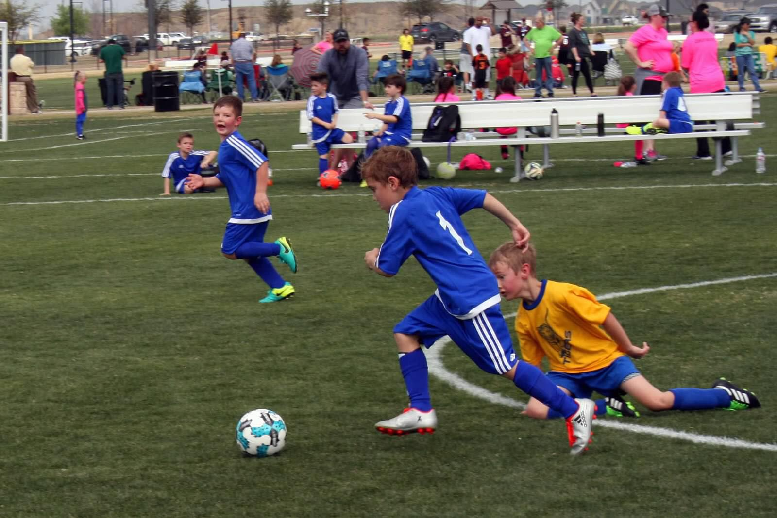 a group of kids compete over a football ball