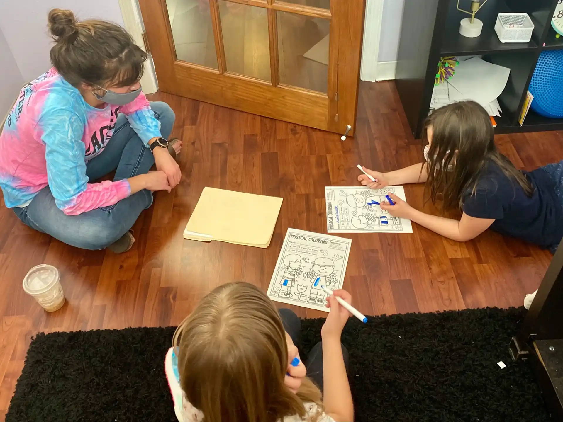 a group of children sitting on the floor writing on paper