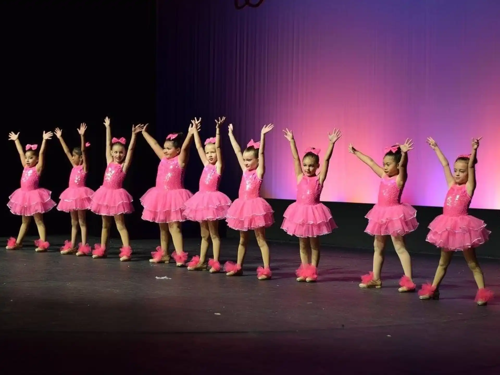 a group of girls in dresses on a stage