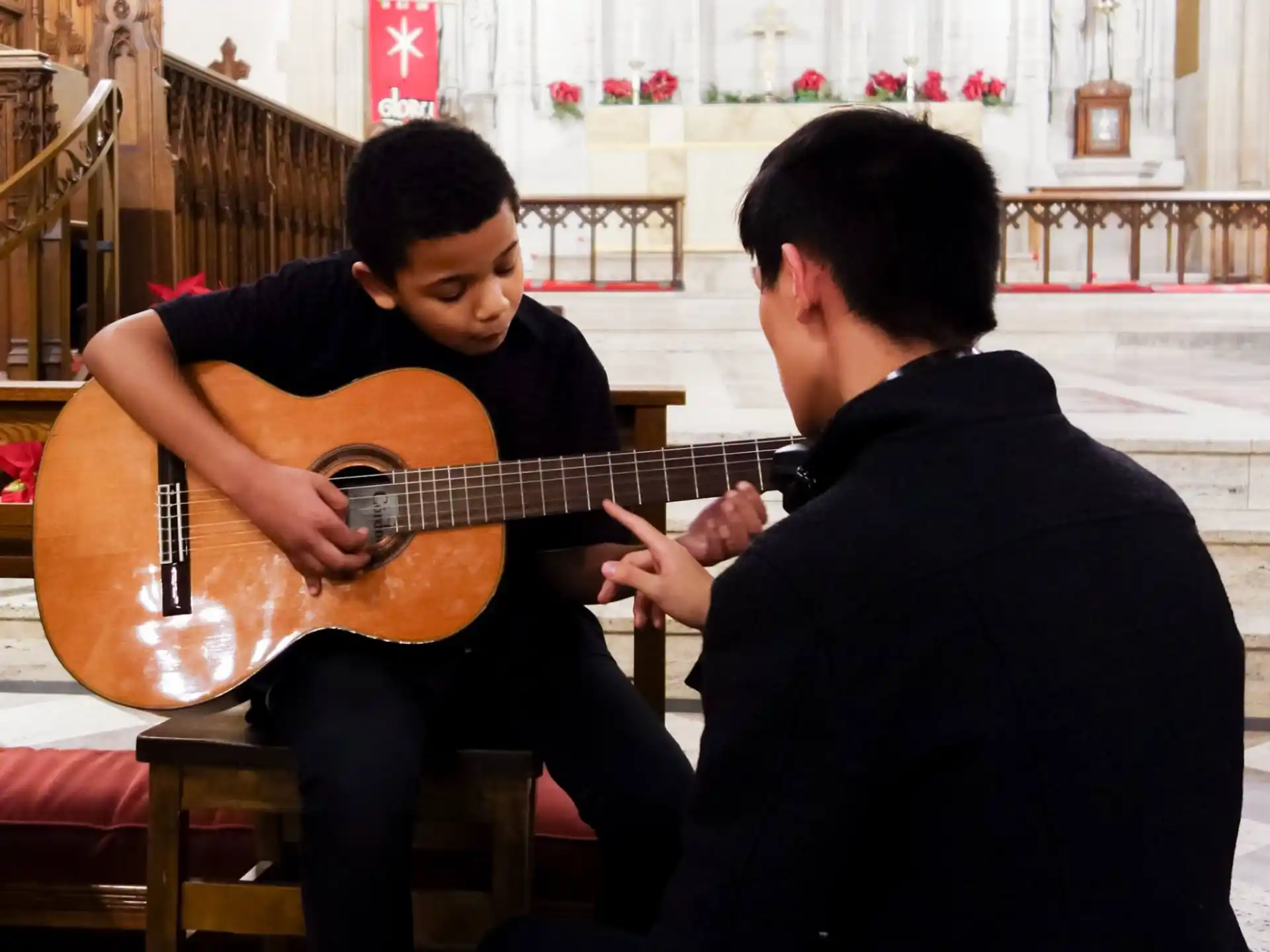 a man playing a guitar next to another man