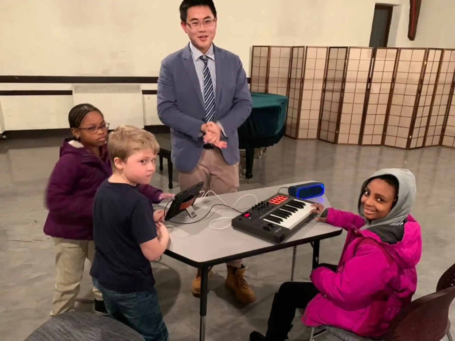 a person standing next to a group of children sitting at a table
