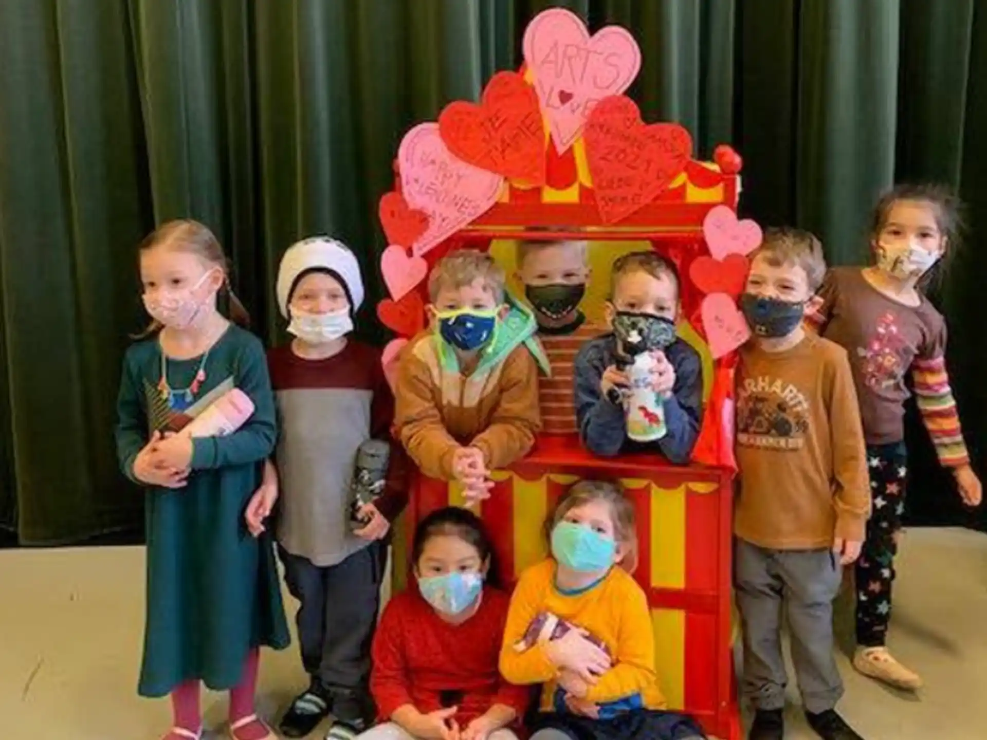 a group of children posing for a photo with a person in a garment
