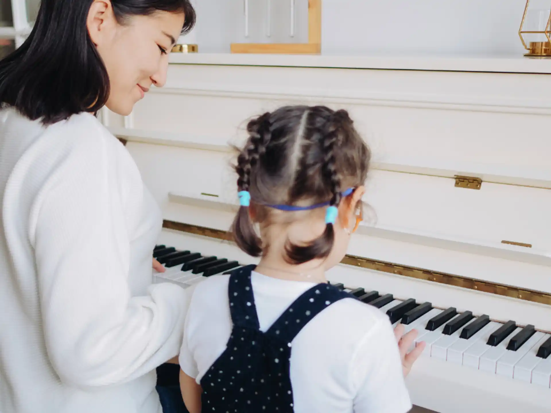 a woman playing a piano with a young girl