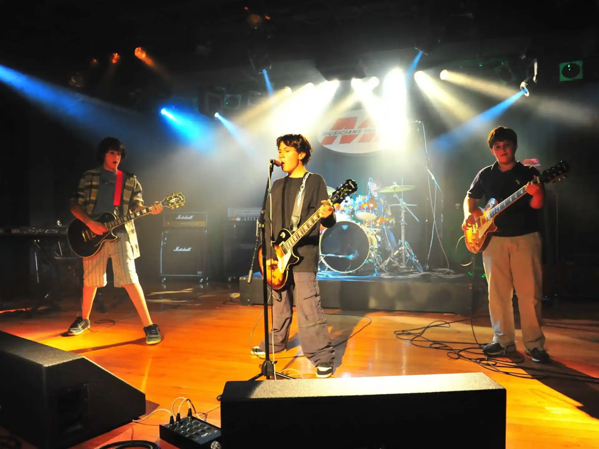 a group of men playing guitars on a stage