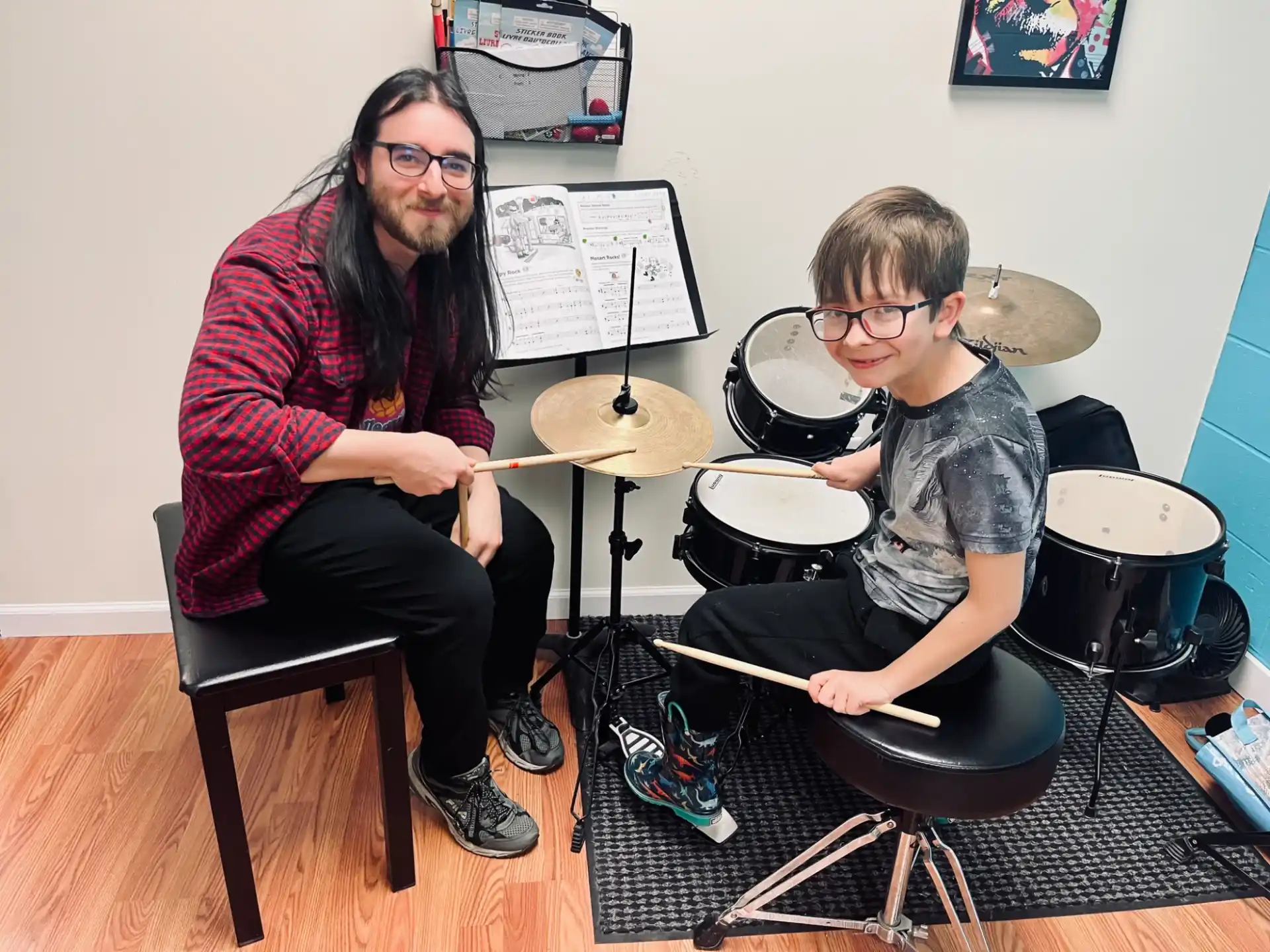 a person and a boy playing drums