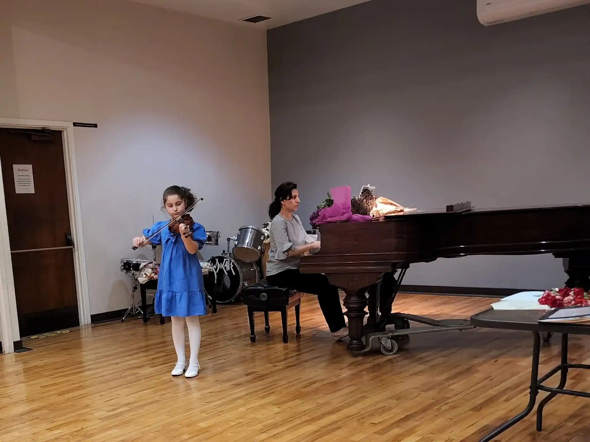 a girl standing next to a person playing a piano
