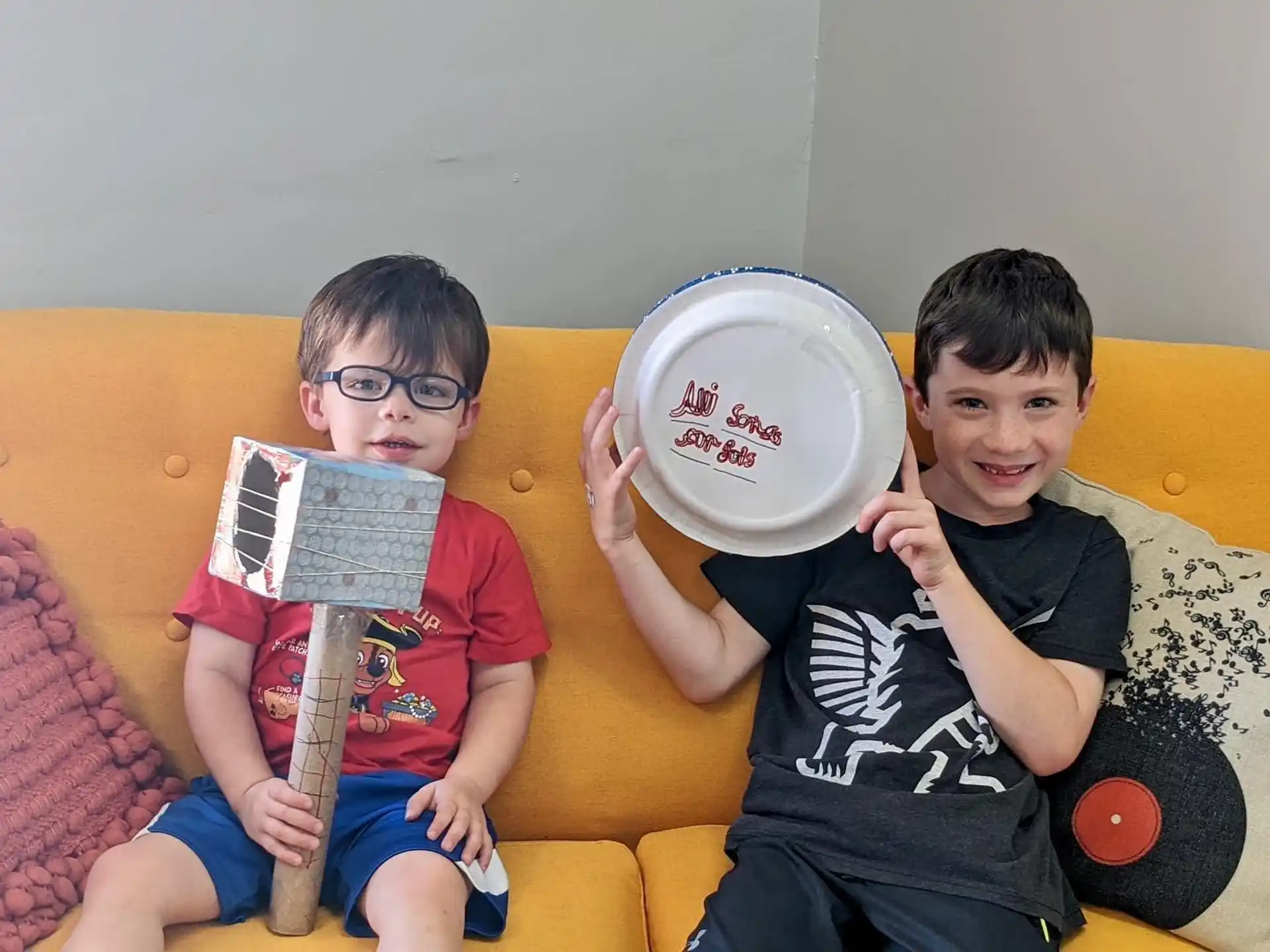 a couple of boys sit on a couch holding a frisbee