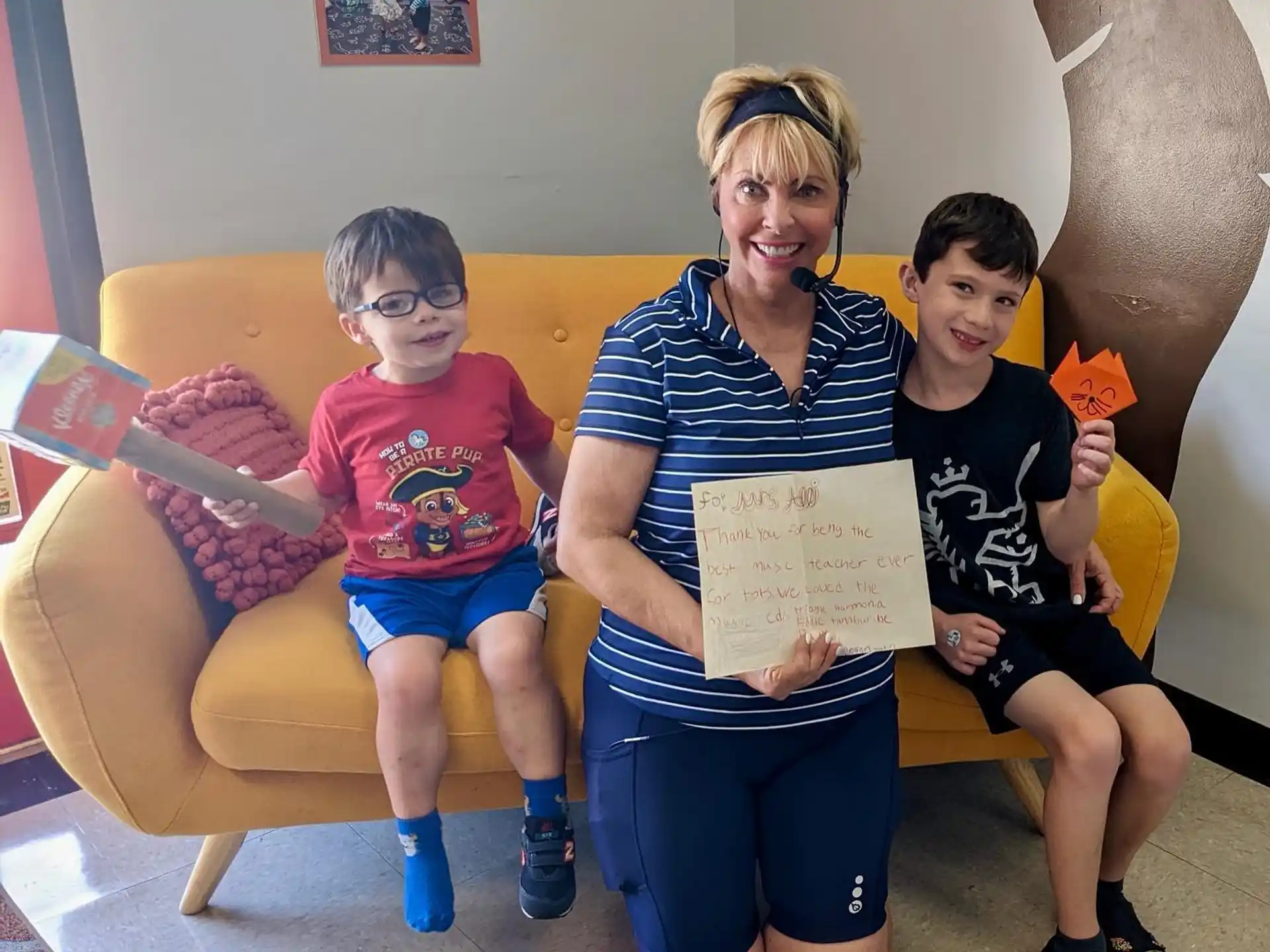 a group of kids sitting on a couch holding a piece of paper