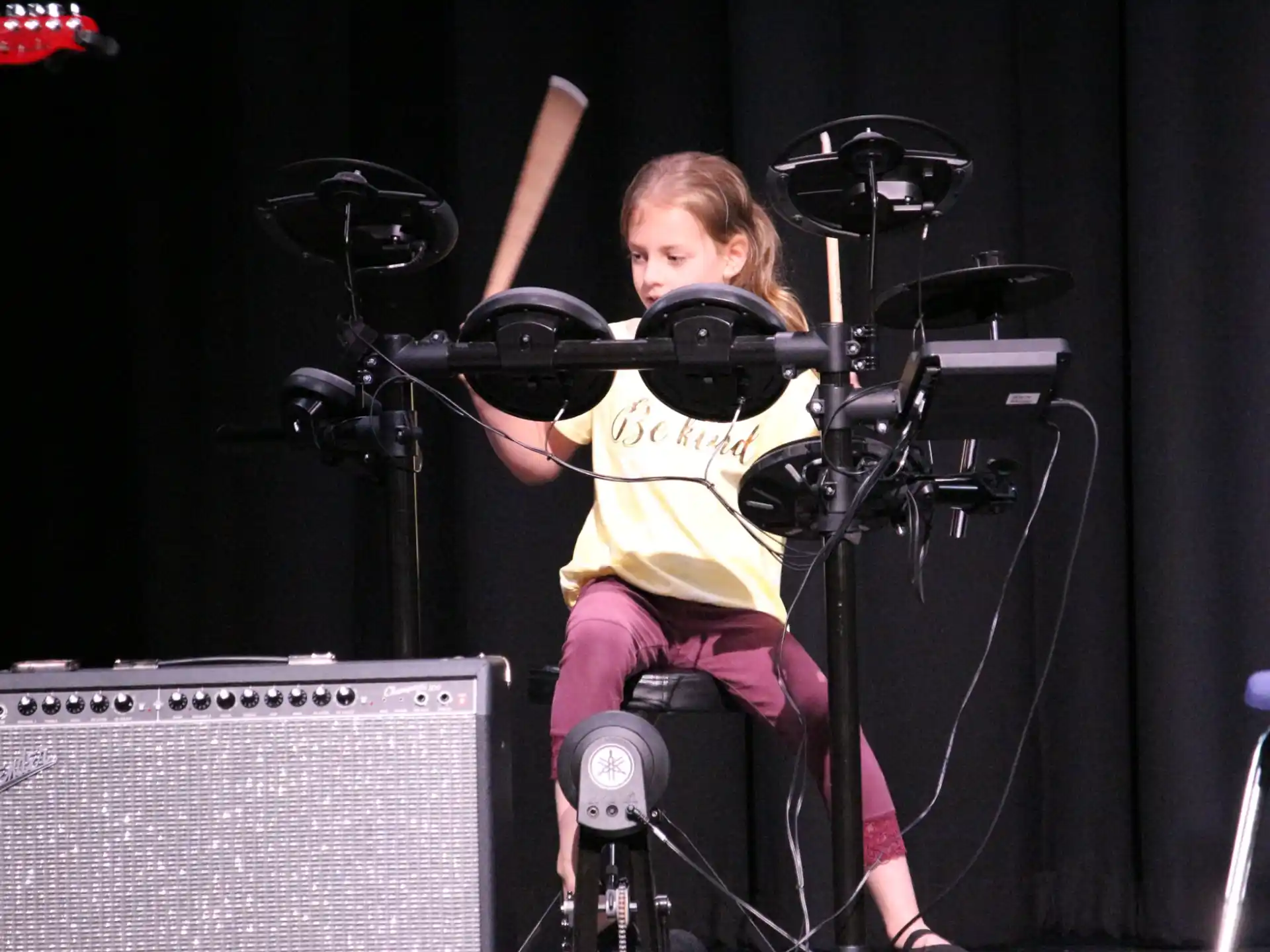 a girl sitting on a stage with a microphone and a camera