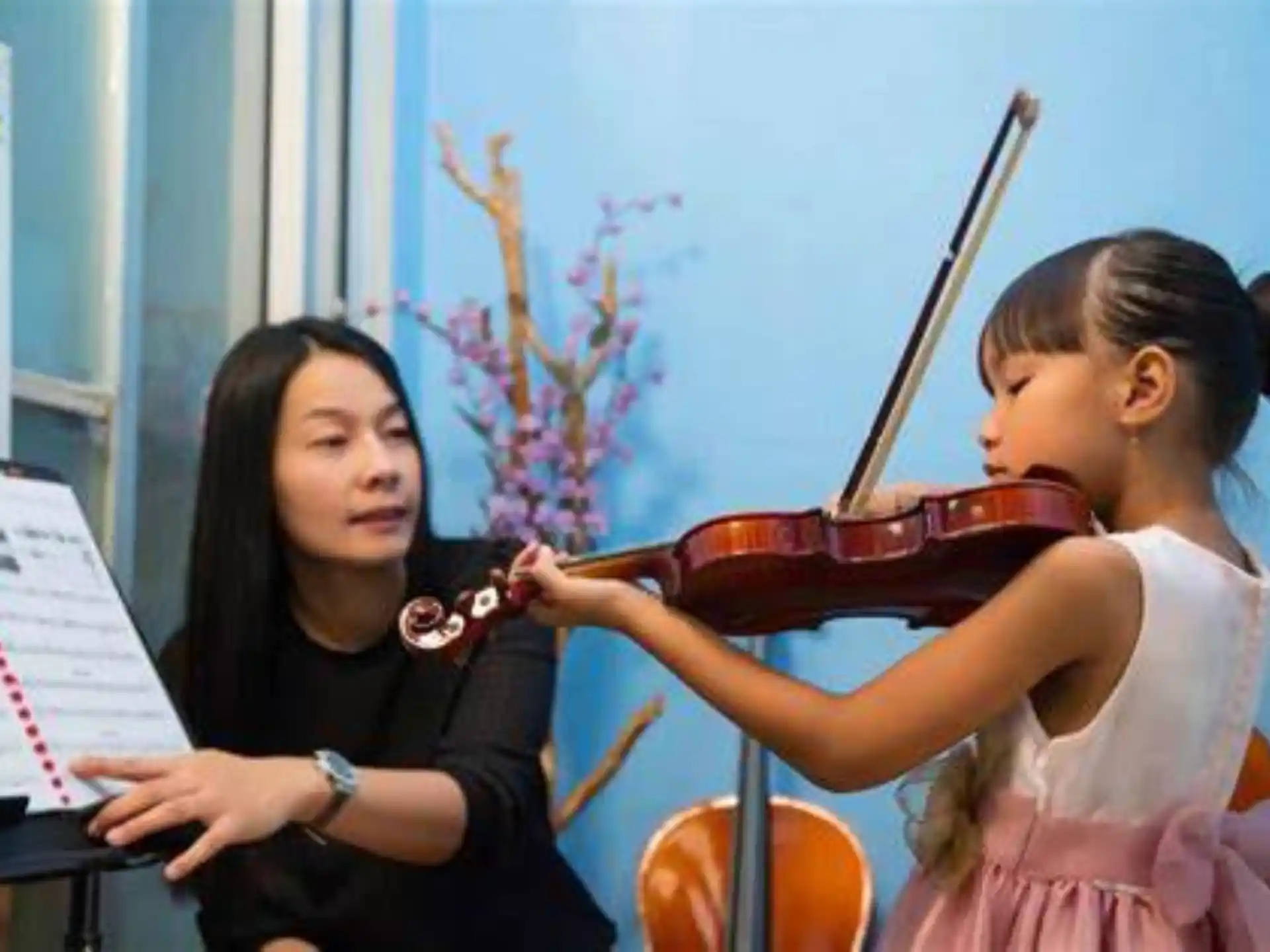 a person playing a violin next to a girl playing a piano