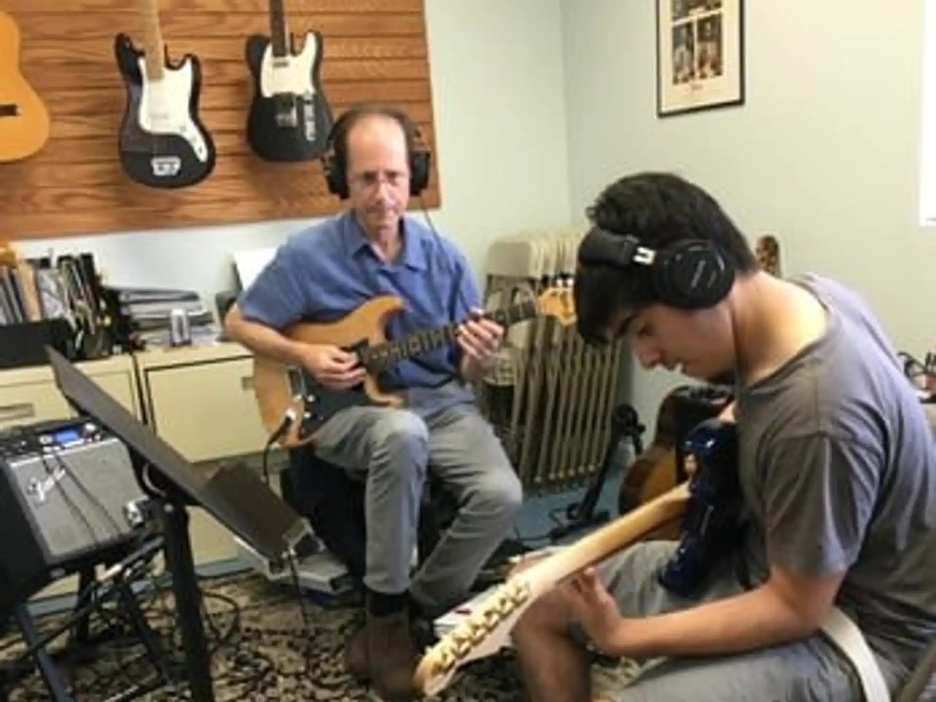 a man playing guitar next to a man wearing headphones