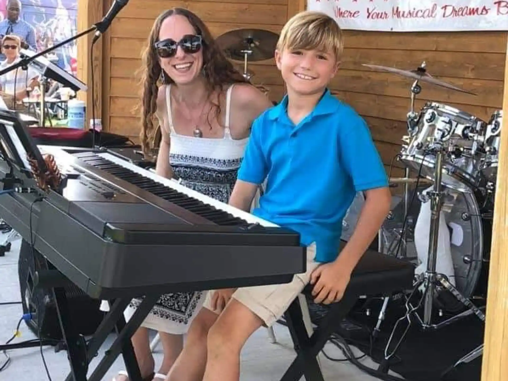 a boy and girl sitting at a piano
