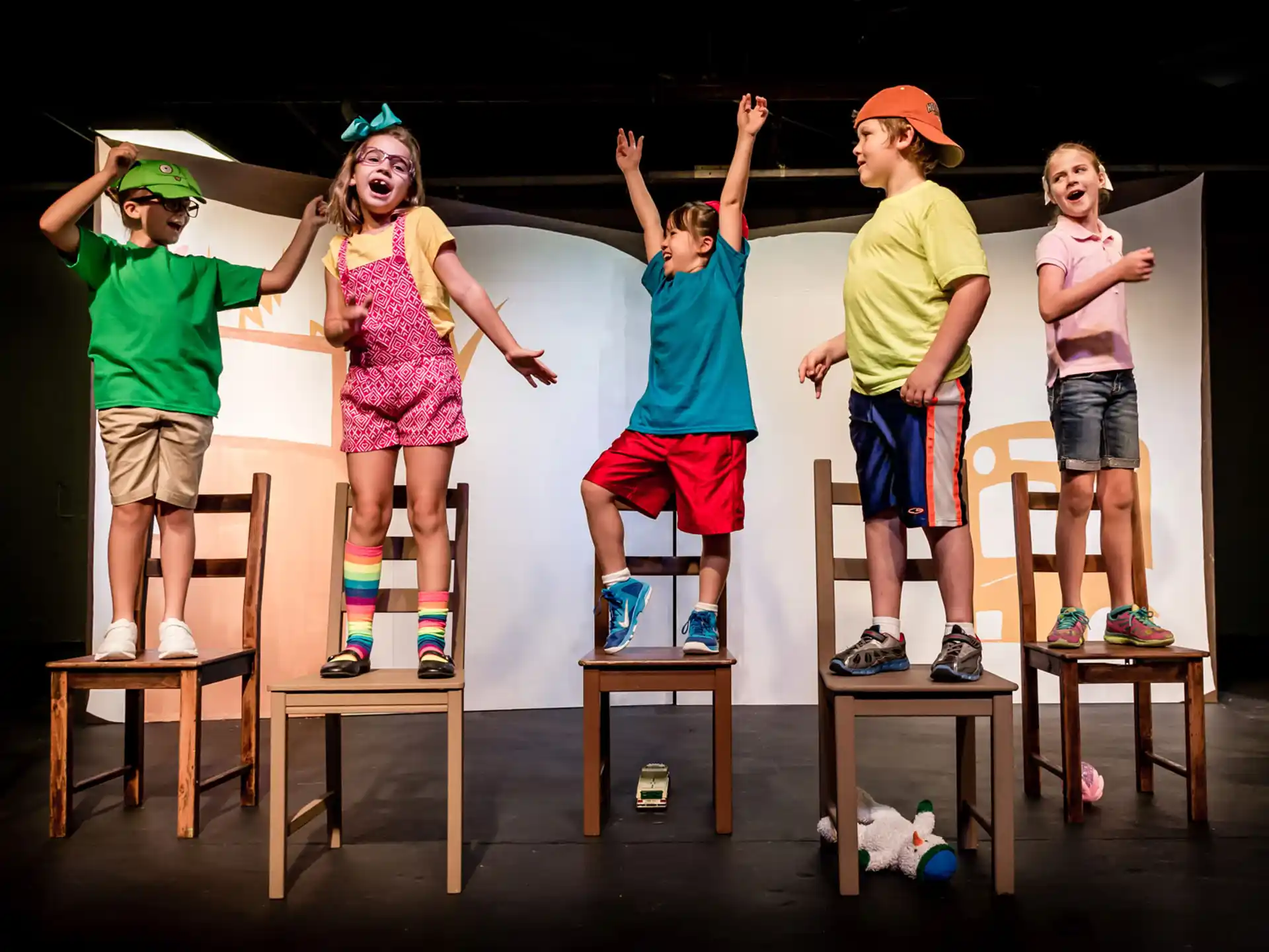 a group of kids standing on wooden chairs