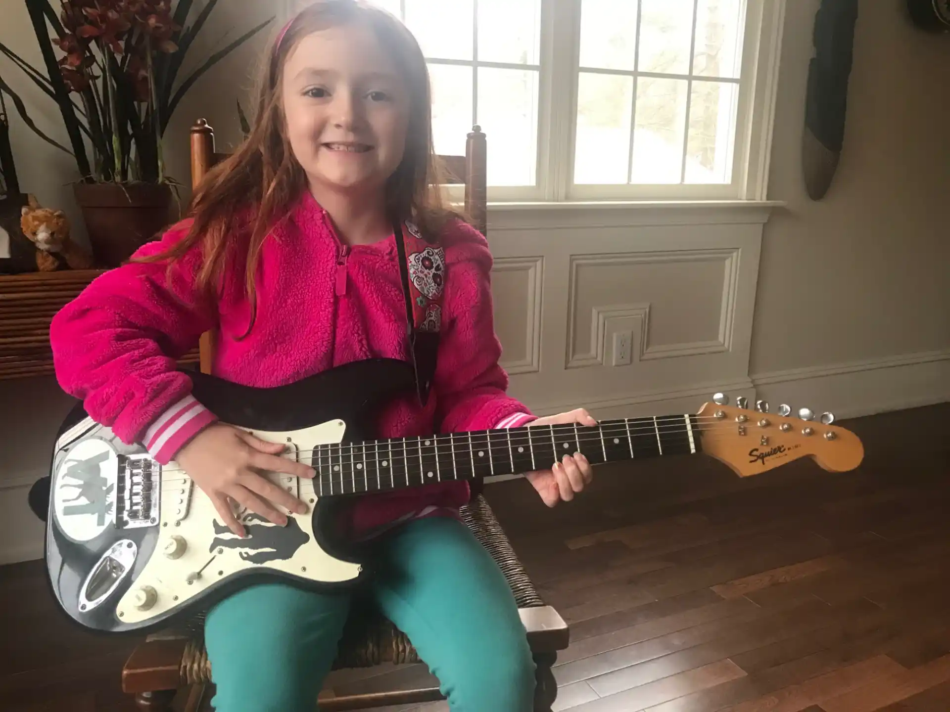 a girl sitting on the floor playing a guitar