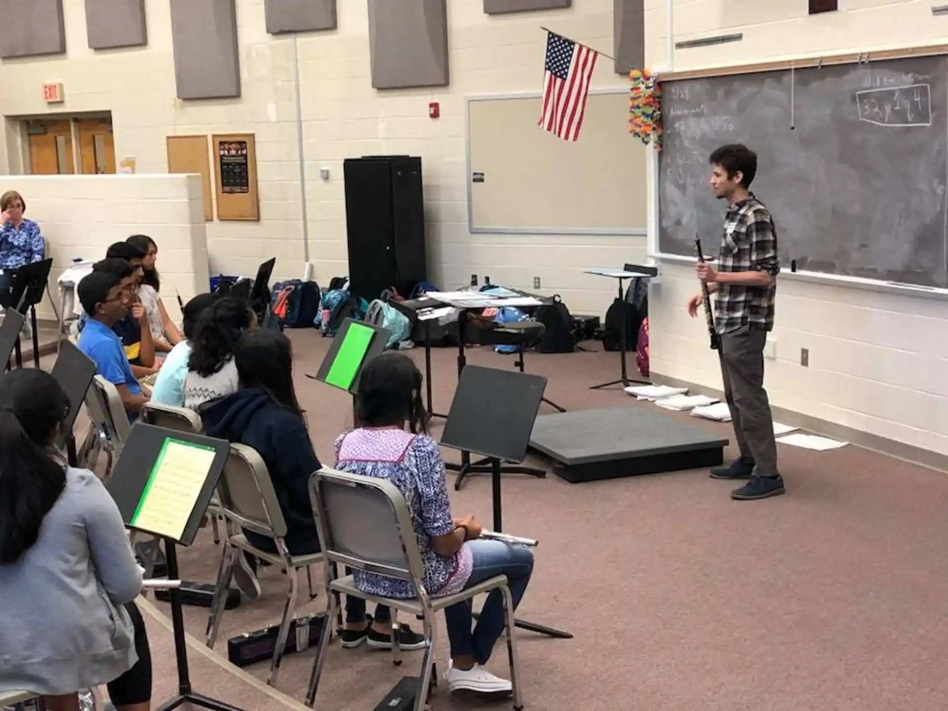 a person standing in front of a classroom with a group of people sitting in chairs
