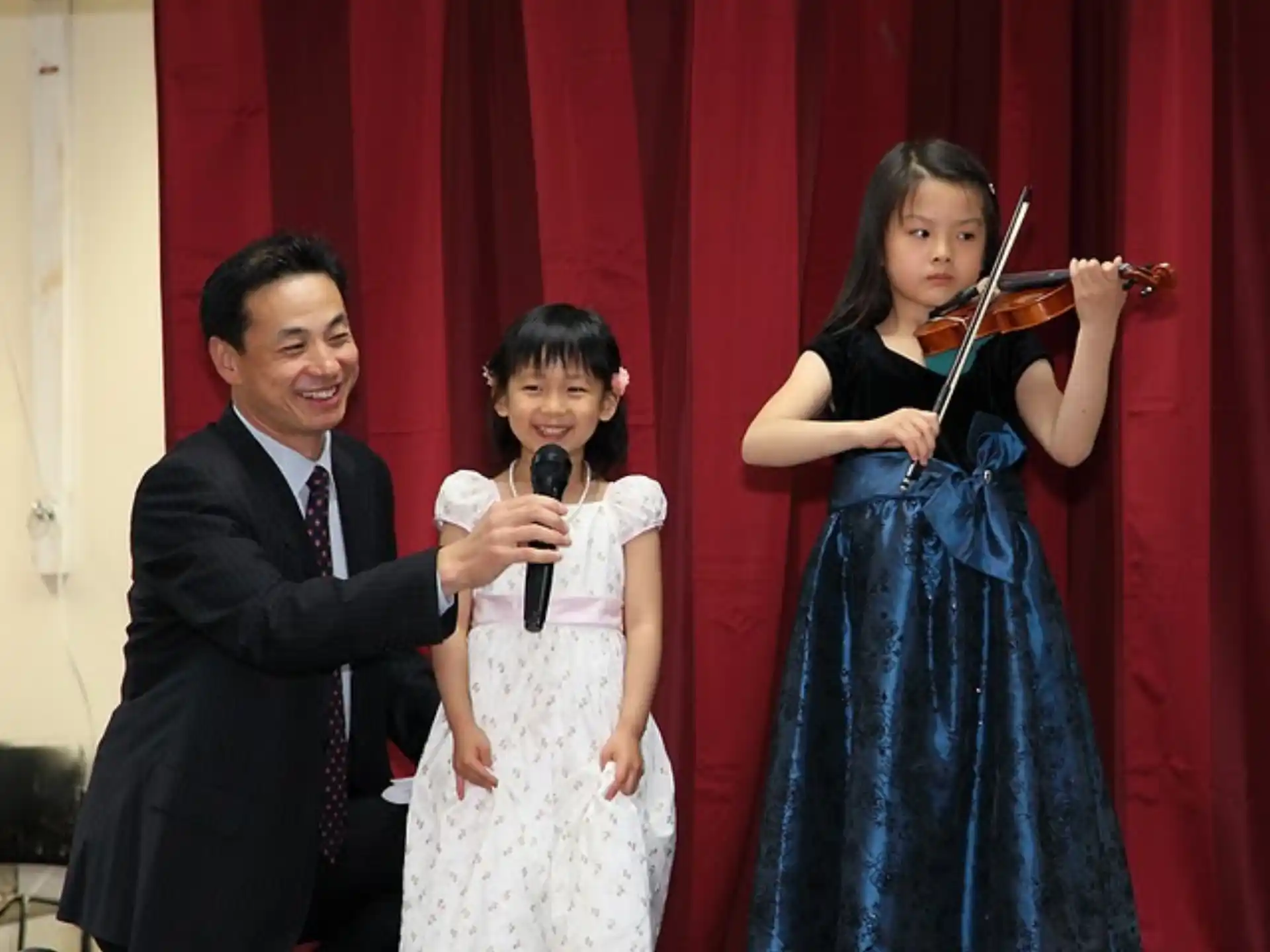 a man and a woman playing the violin with a girl in a dress