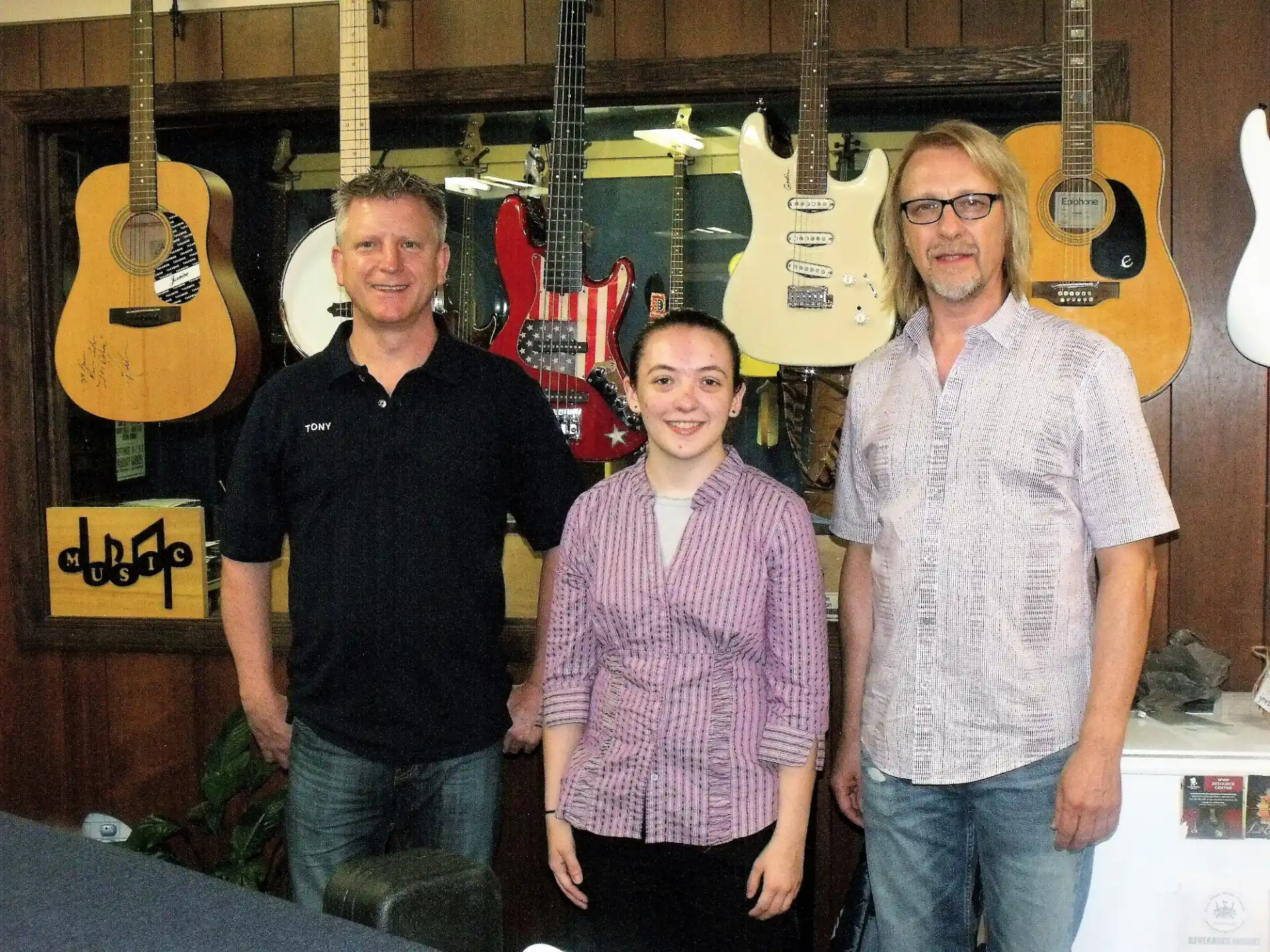 a group of people posing for a photo in front of guitars