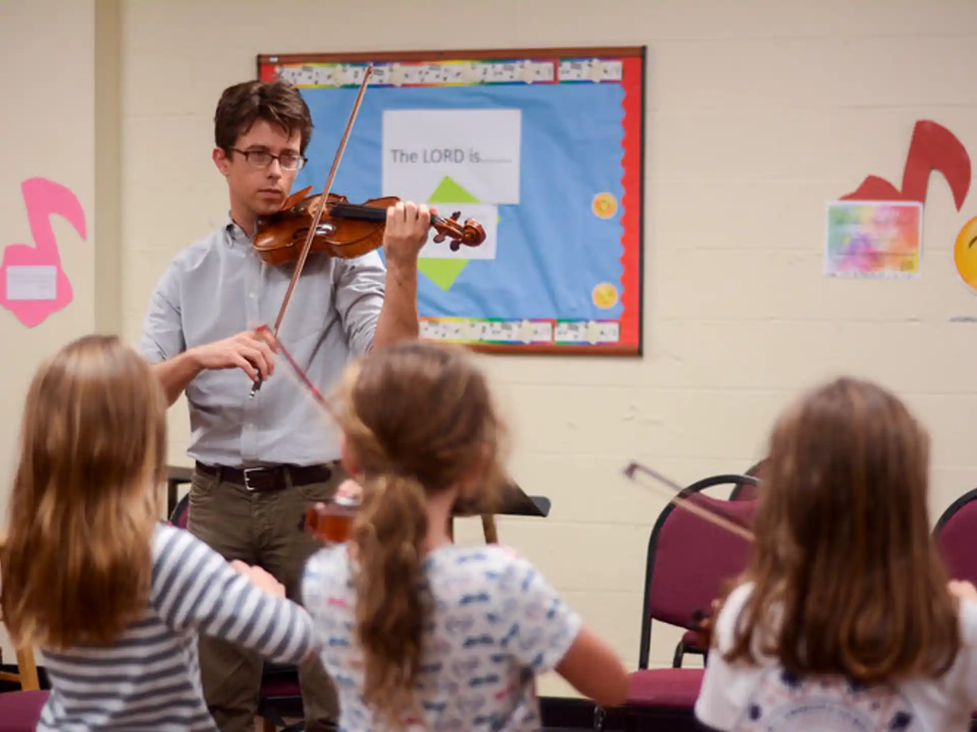a person playing a violin in front of a group of children