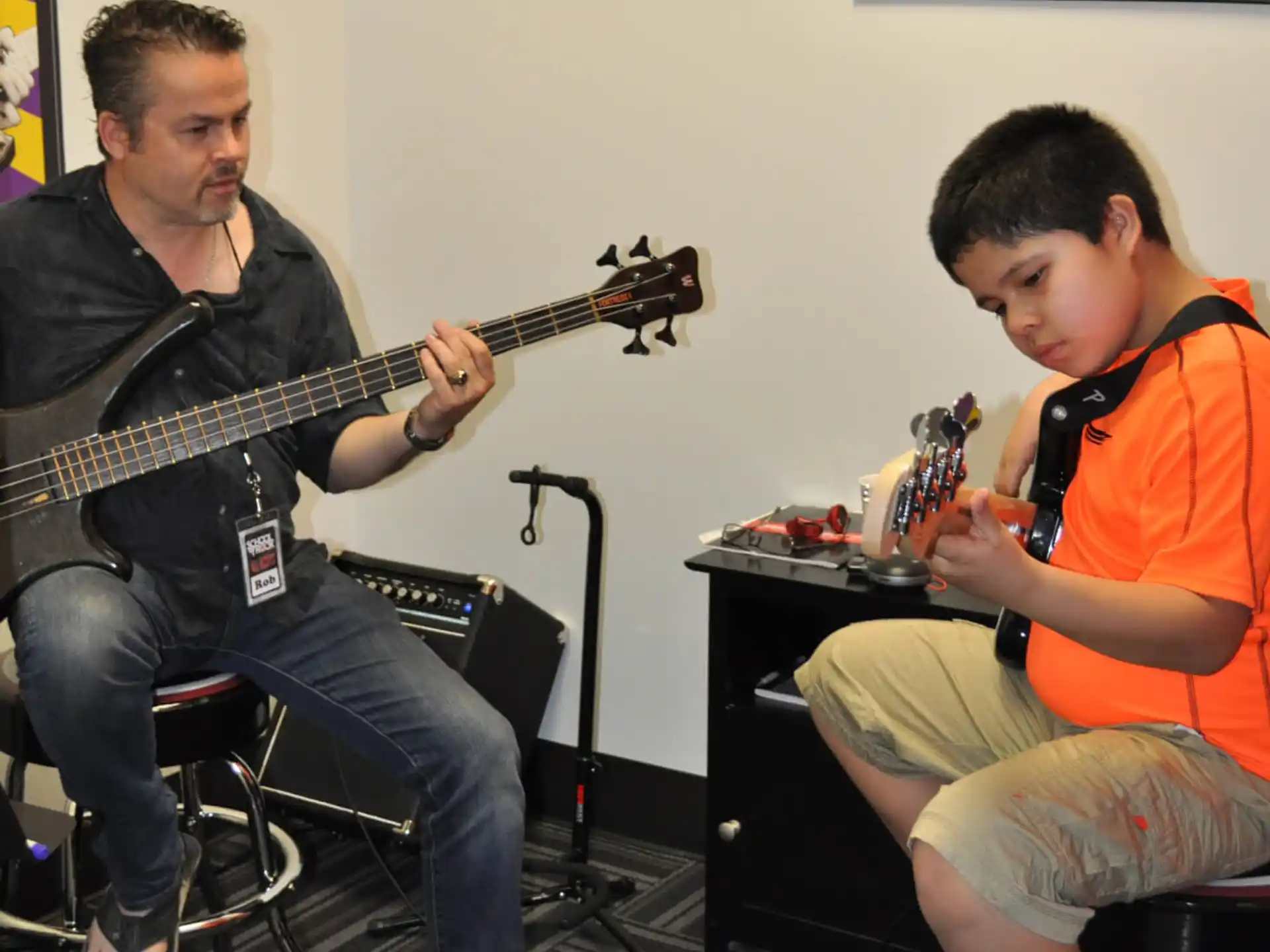 a man playing guitar next to a boy sitting on a stool