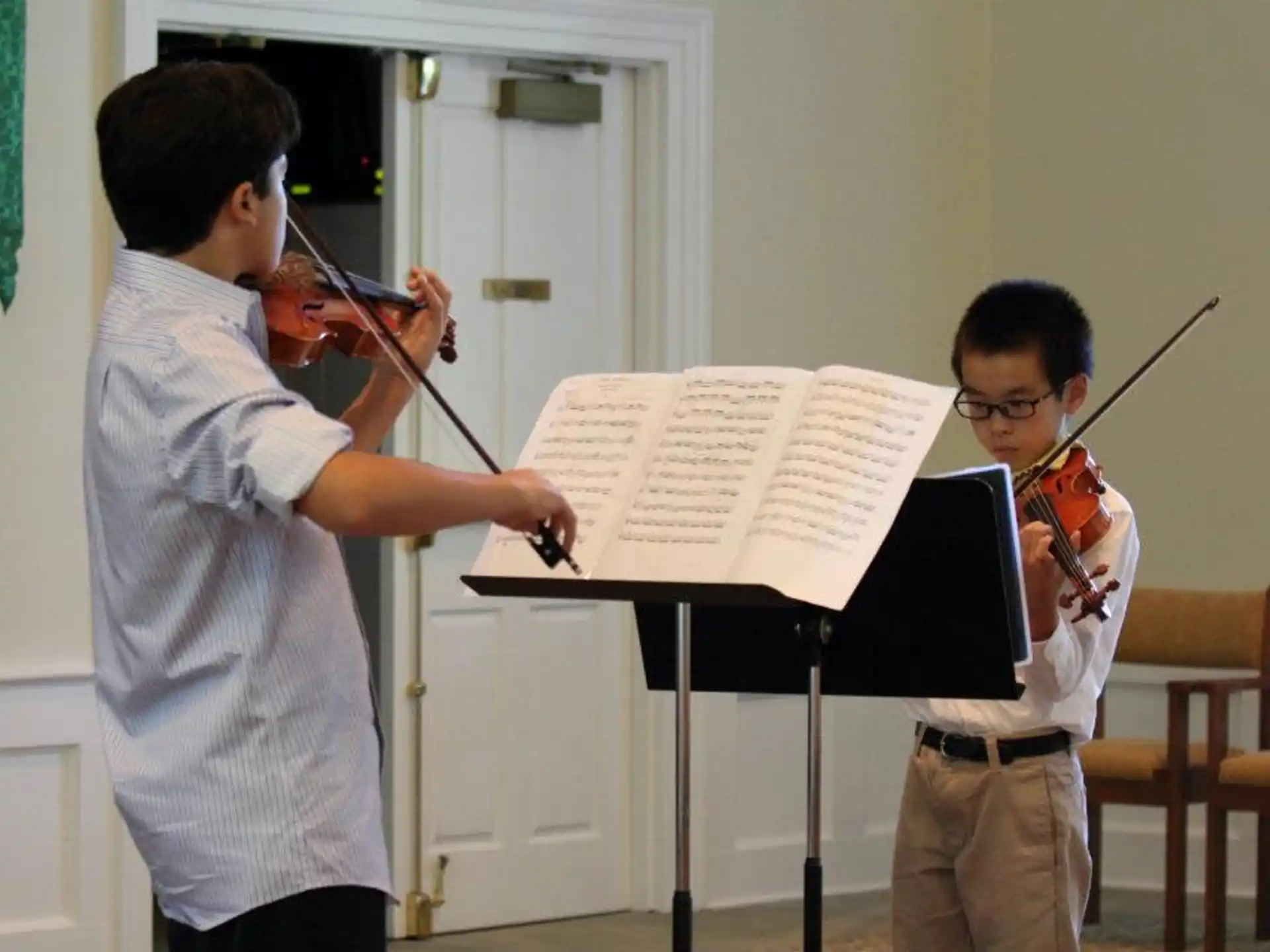 a person playing a violin next to a boy playing a piano