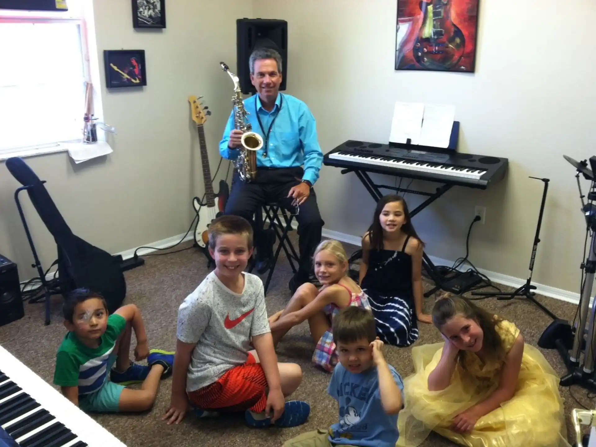 a group of kids sitting on the floor in front of a person playing a guitar