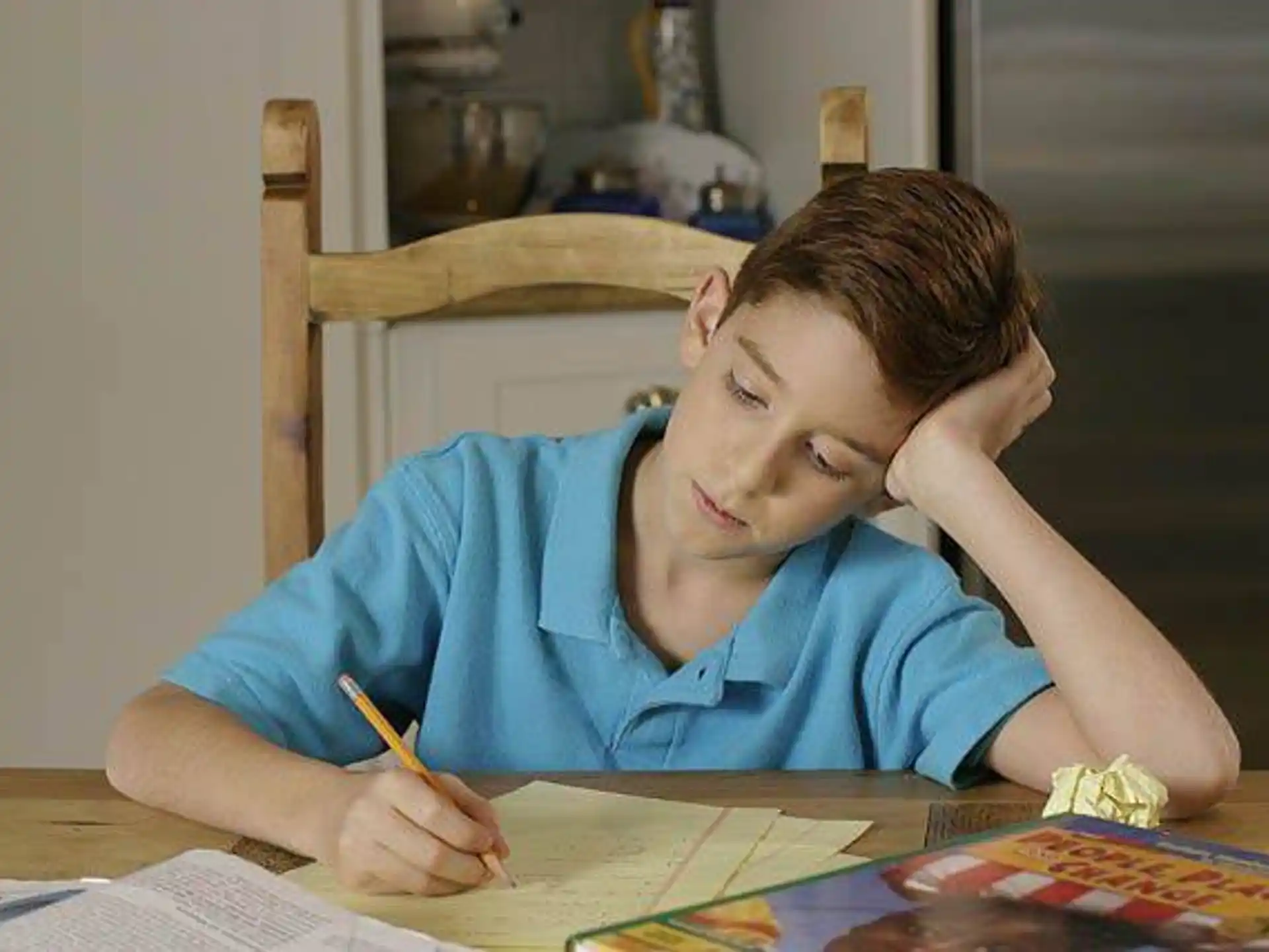 a person sitting at a table writing on a book