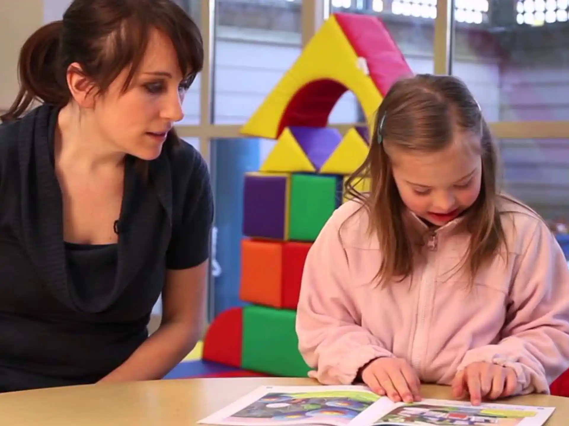 a woman and a girl looking at a book