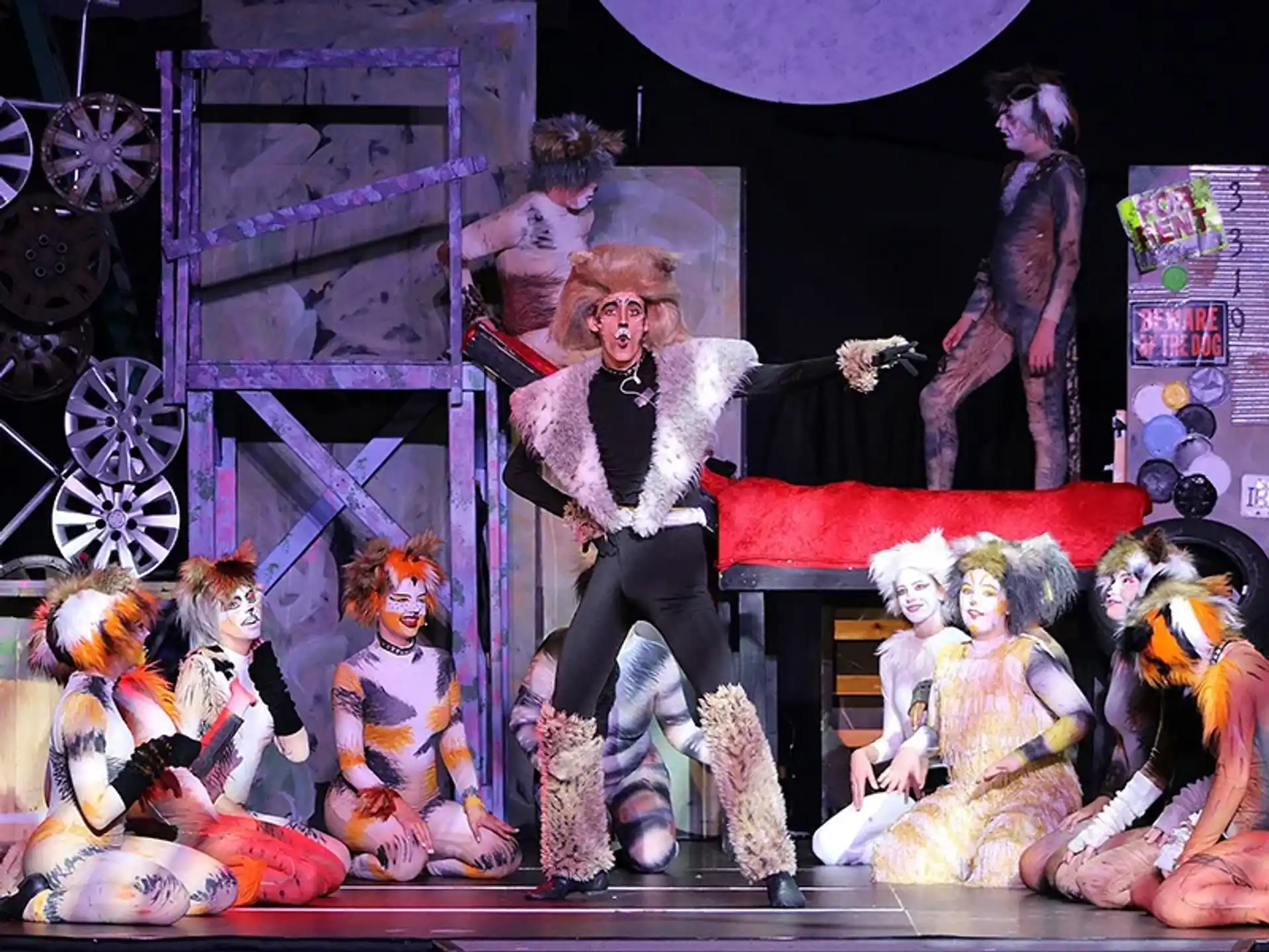 a person sitting on a stage with a group of dolls