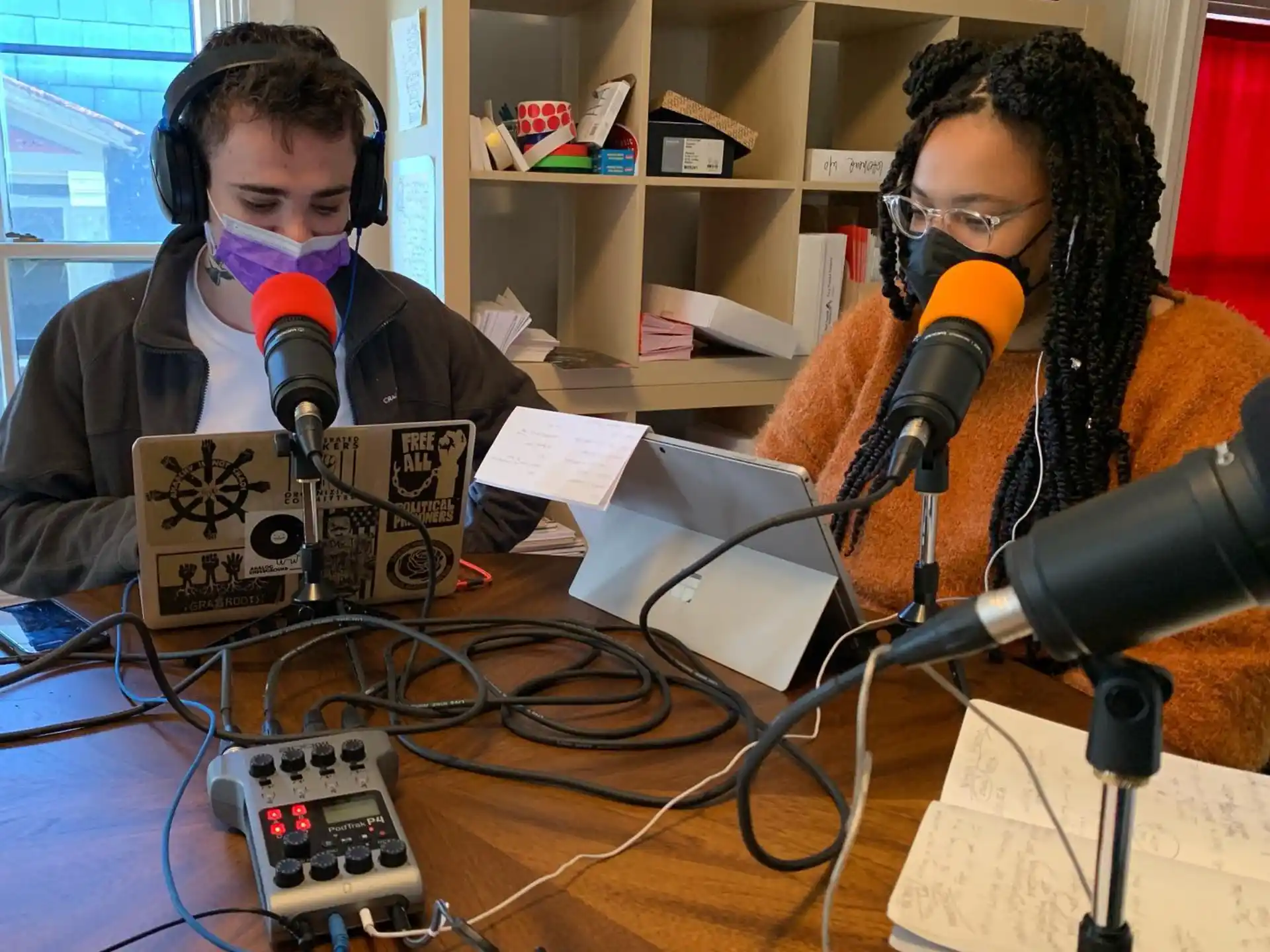 a couple of people sitting at a table with microphones and electronic devices