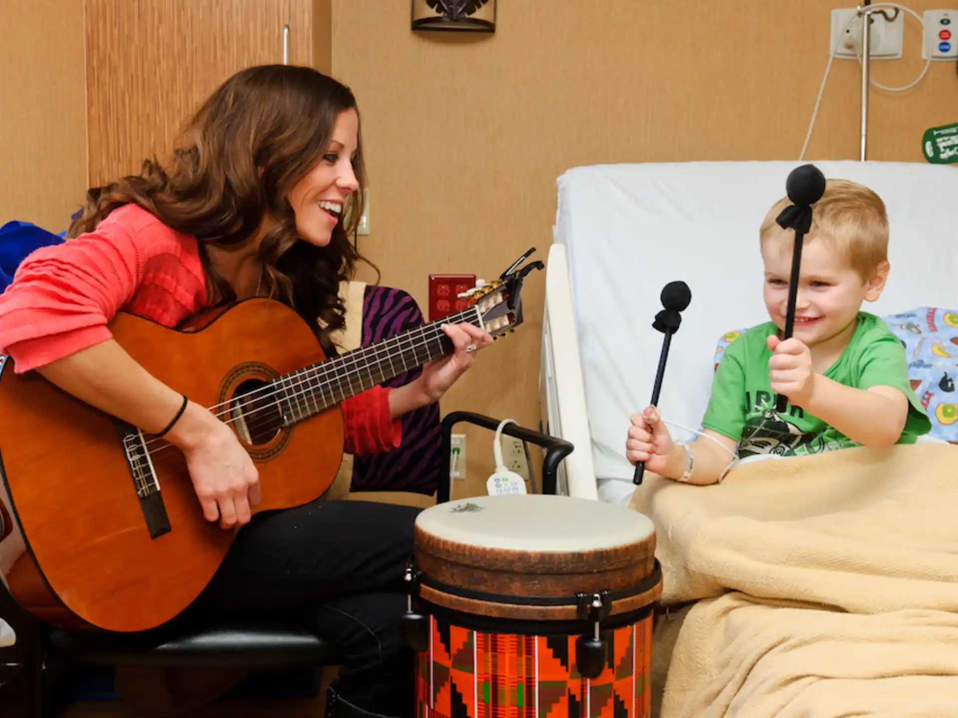 a woman playing a guitar next to a girl playing drums