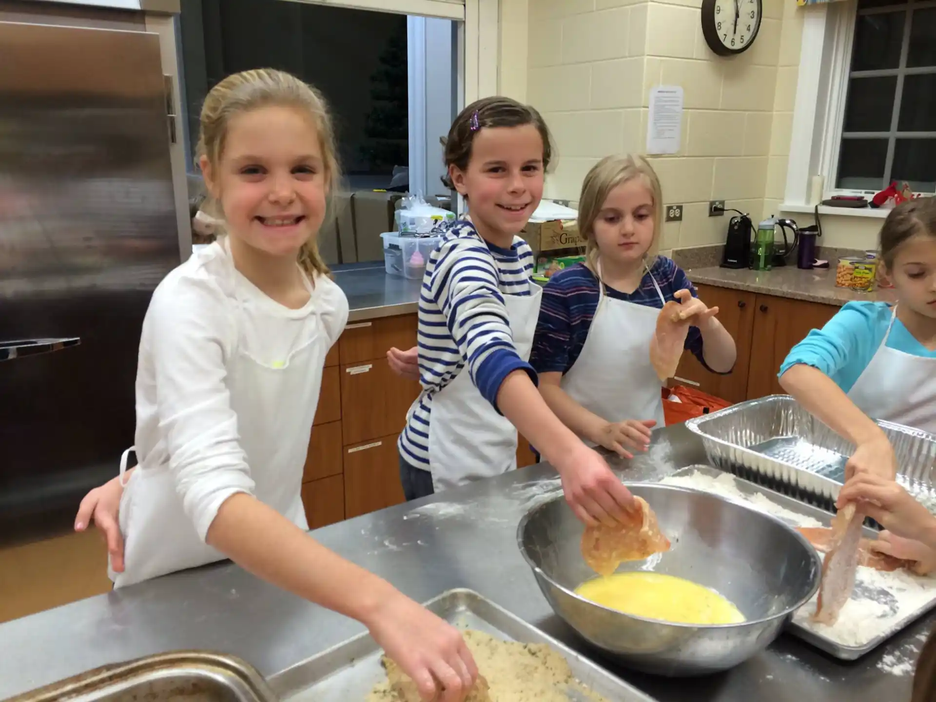 a group of children cooking in a kitchen