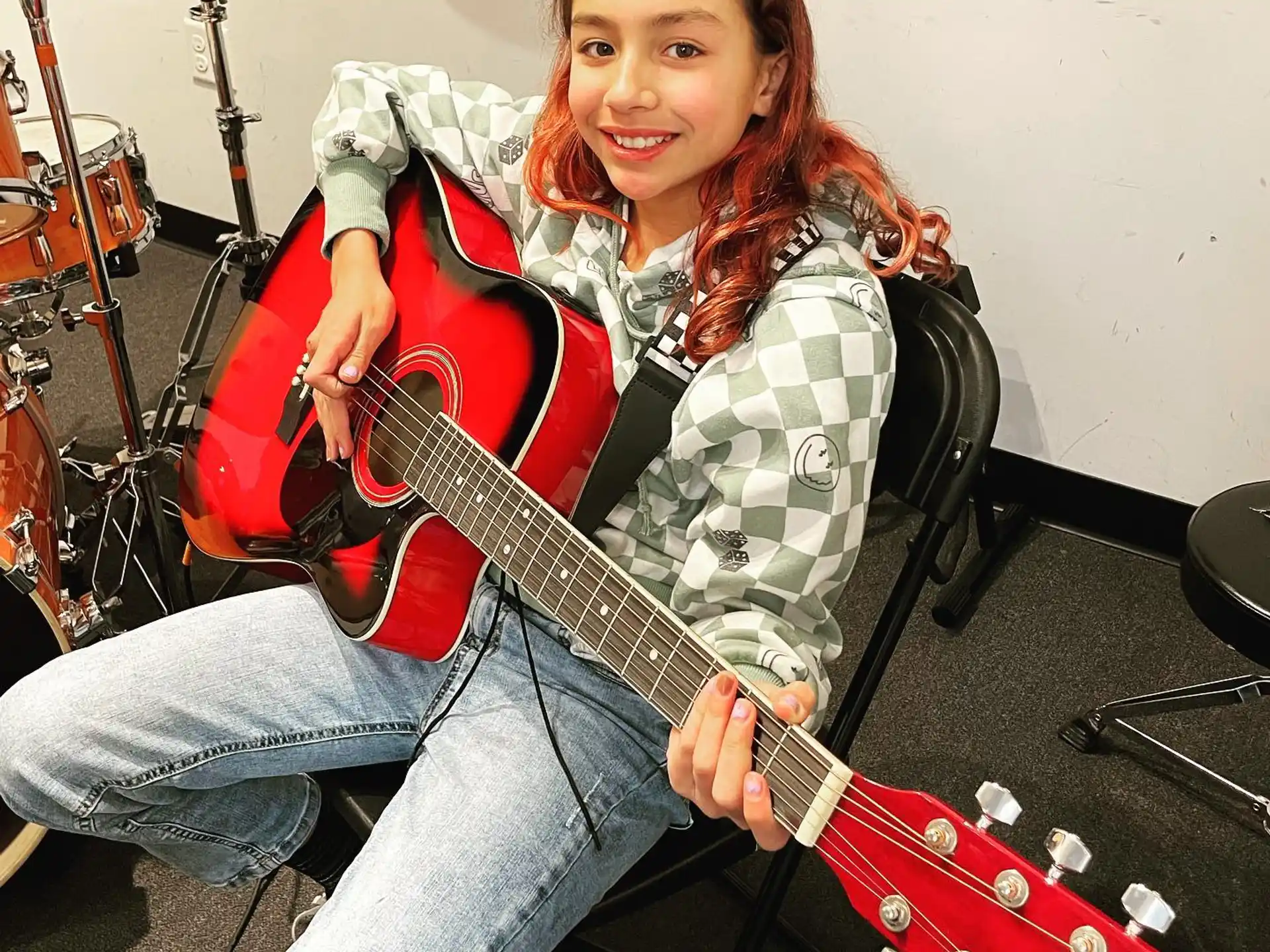 a girl sitting on a chair holding a guitar