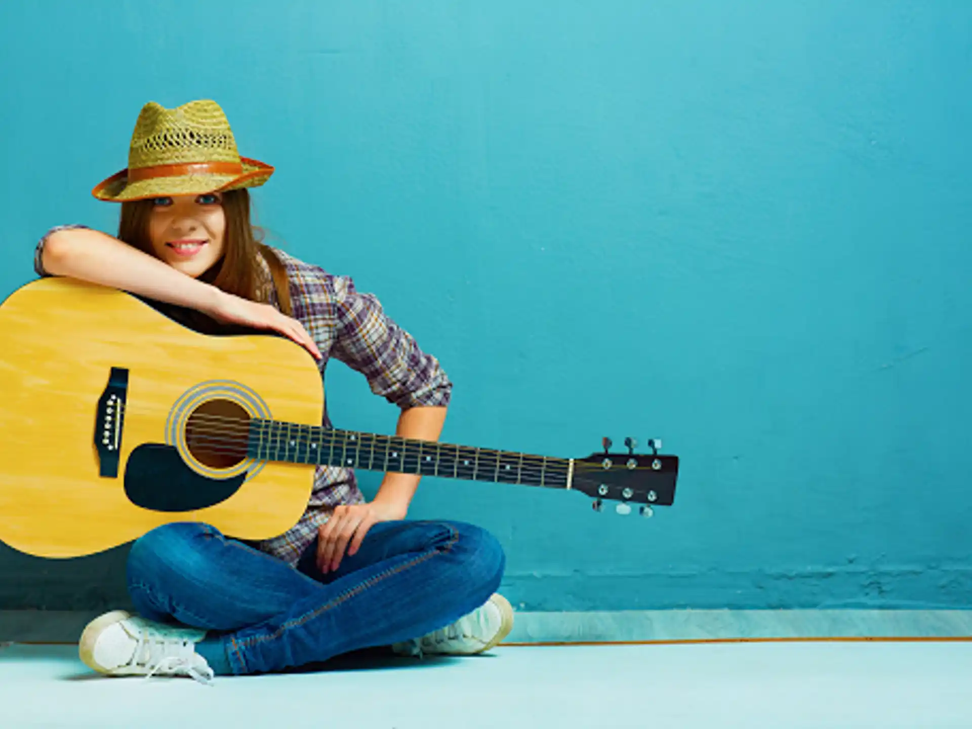 a young girl sitting on the floor playing a guitar
