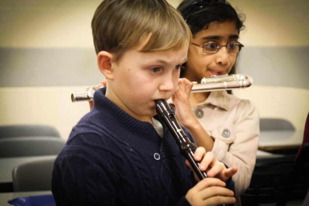 a boy holding a pipe to his mouth and another boy holding a pipe