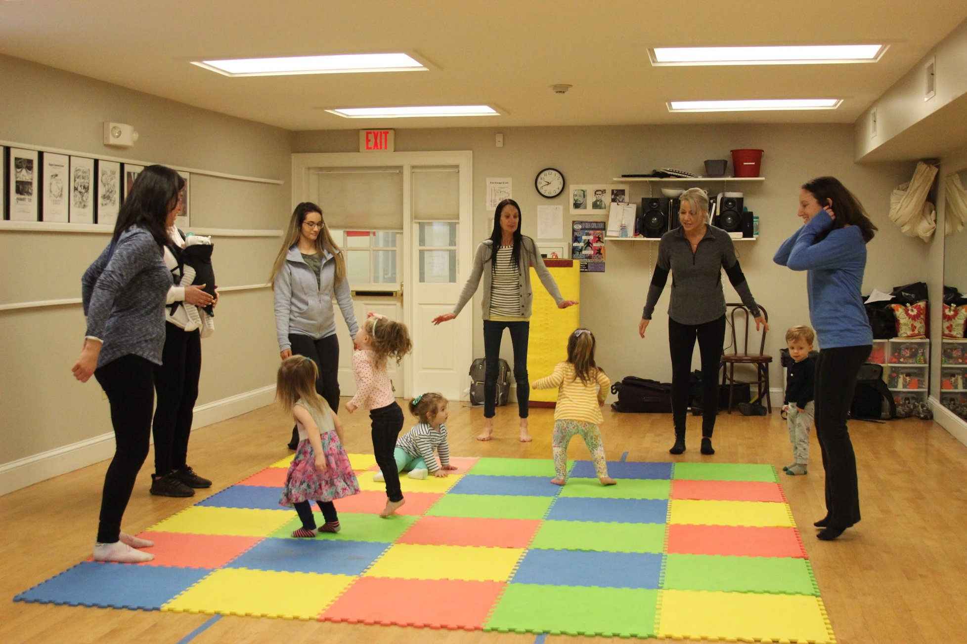 a group of people standing in a room with a rug and a rug