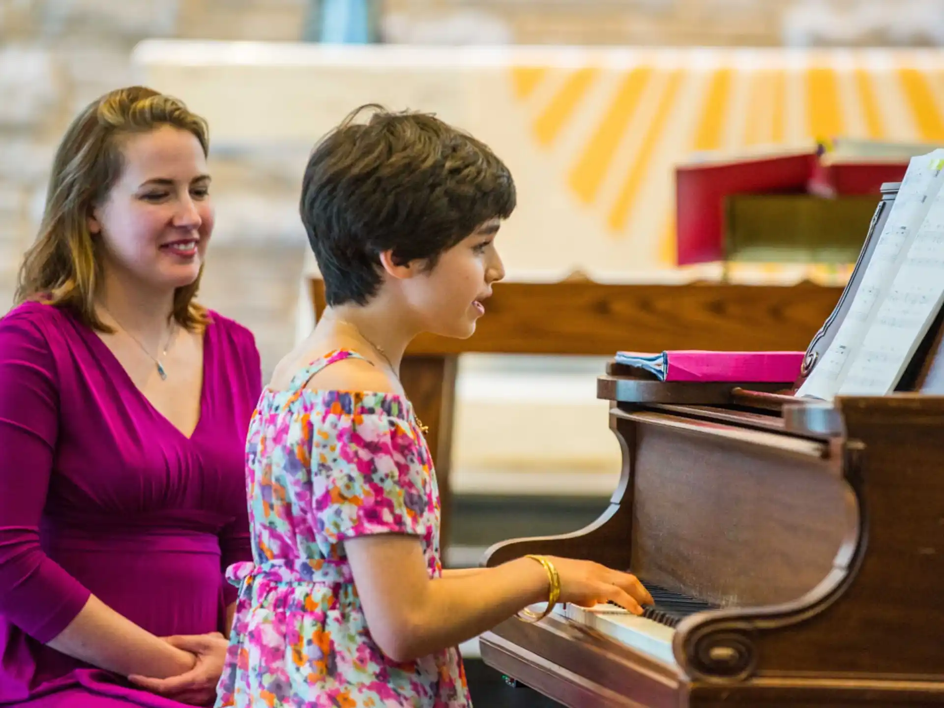 a woman and a child playing piano