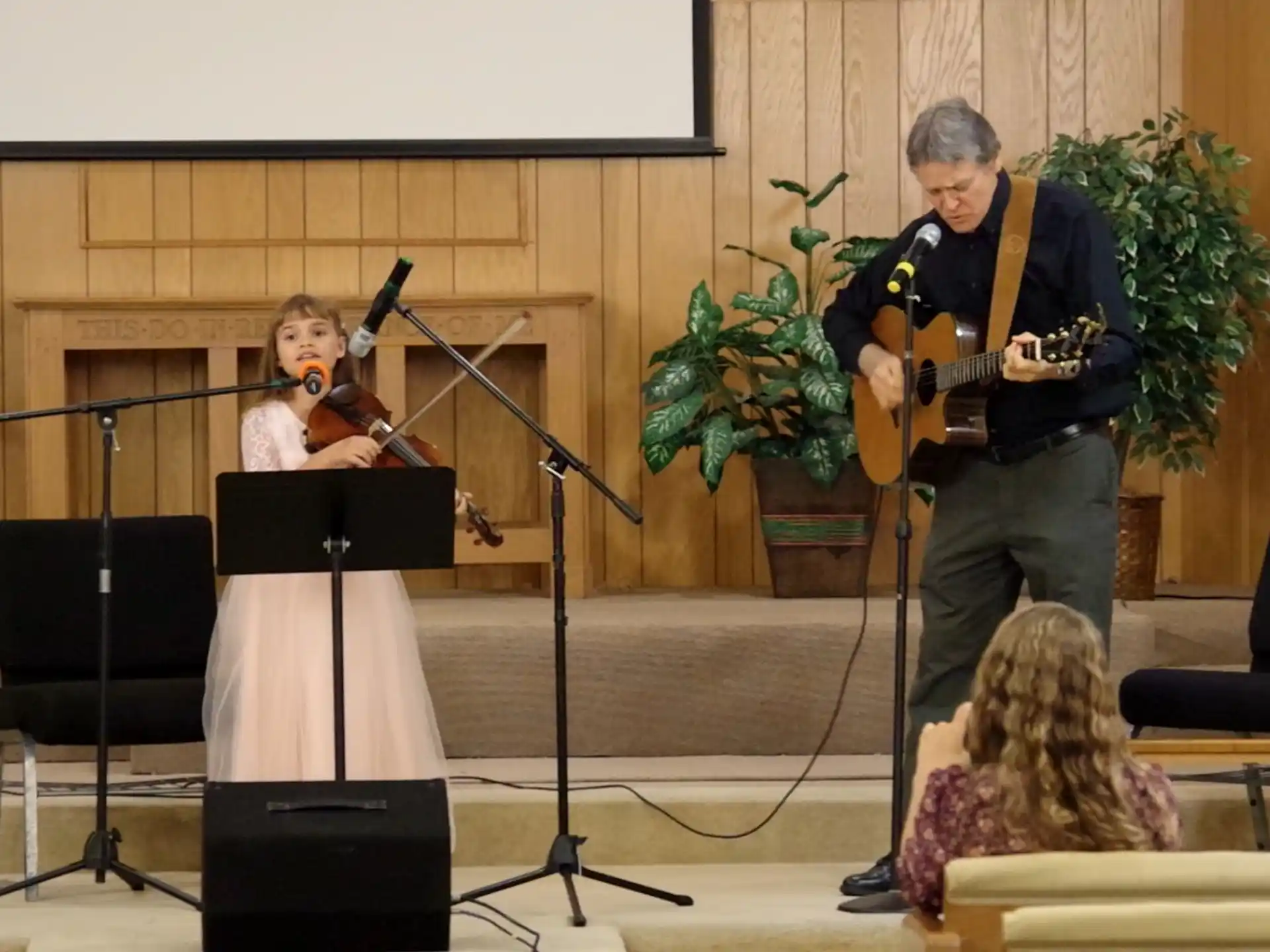 a man playing a guitar next to a woman playing a musical instrument