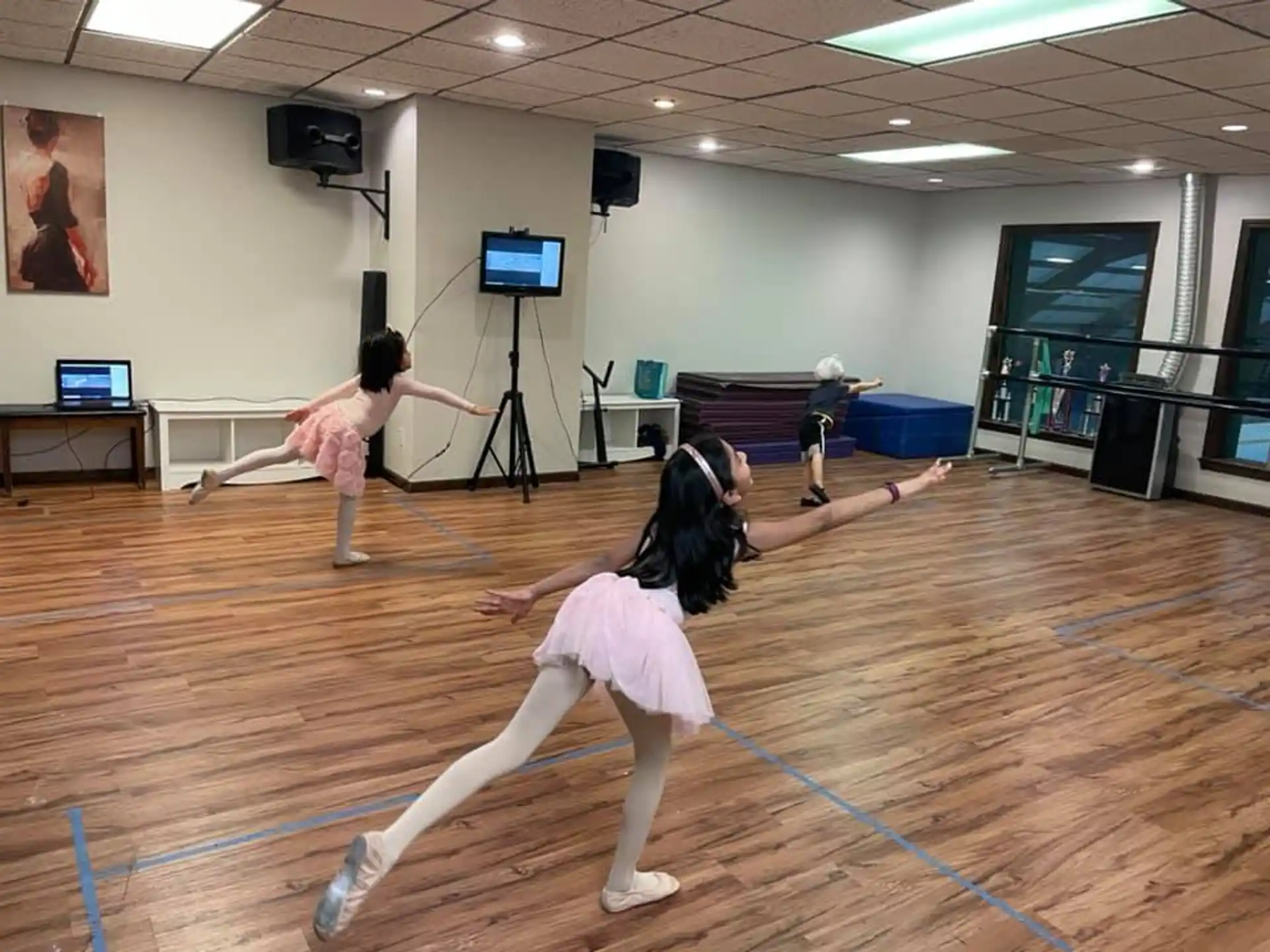 a couple of girls dancing on a mat in a room with a tv and speakers