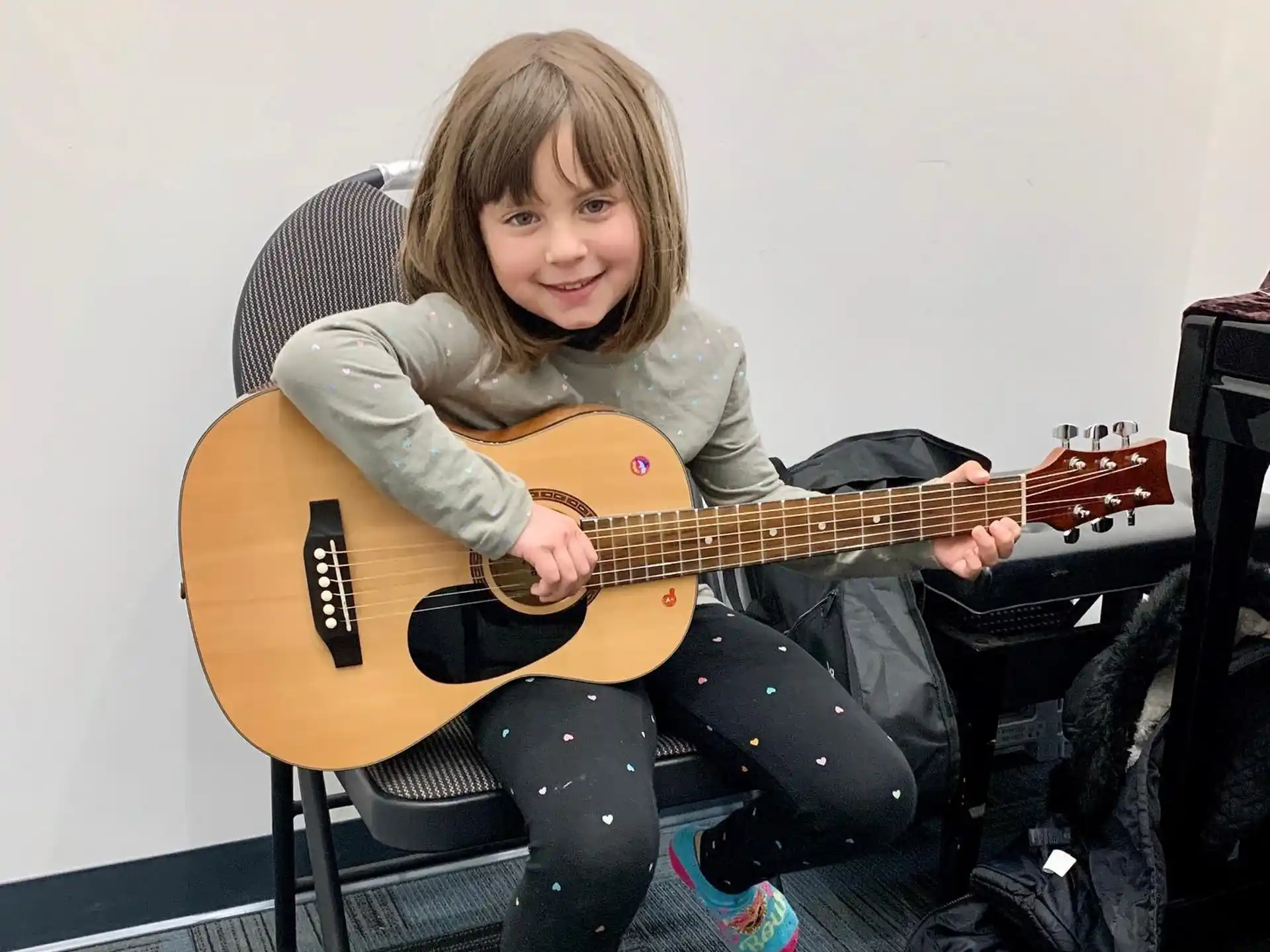 a girl sitting on a chair playing a guitar