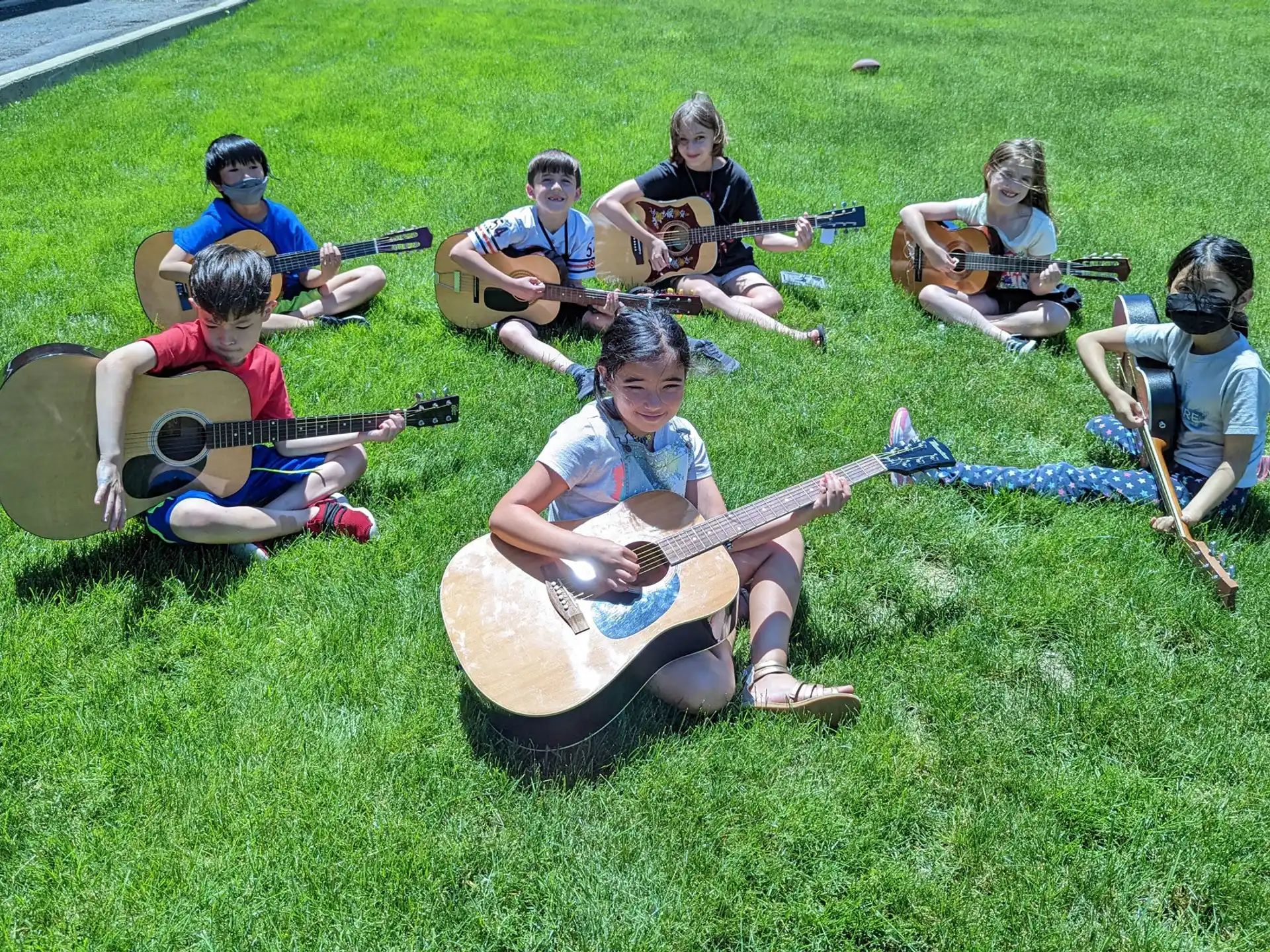 a group of people sitting on the grass playing instruments