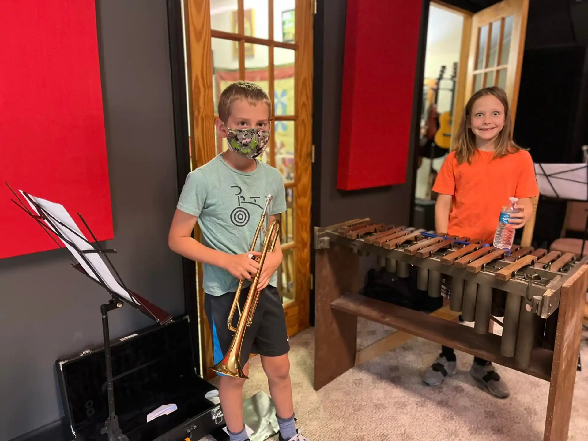 a boy with a mask and a guitar next to a girl with a microphone