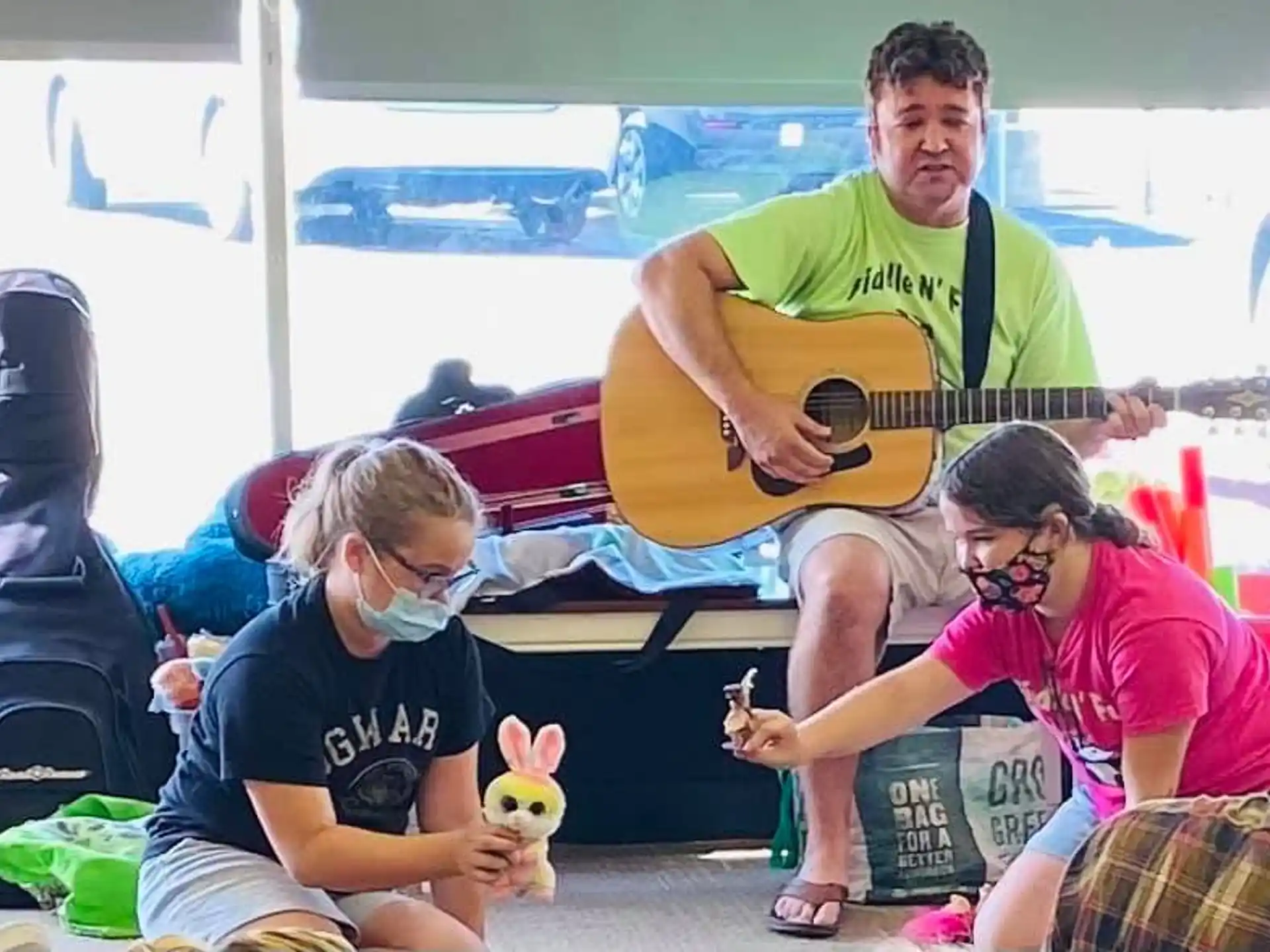 a man playing guitar next to a couple of people sitting on a bench