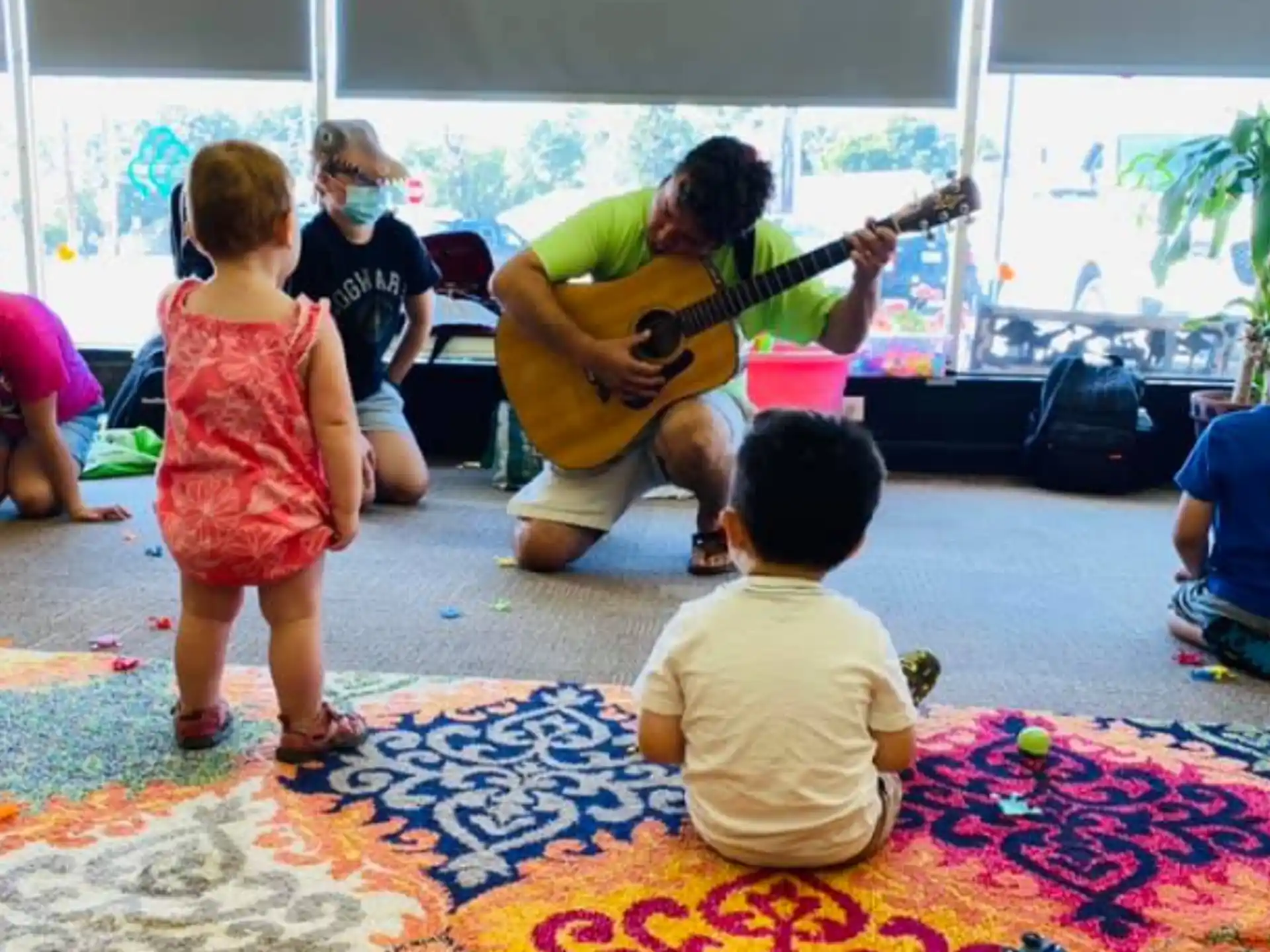 a person playing guitar in front of a group of children