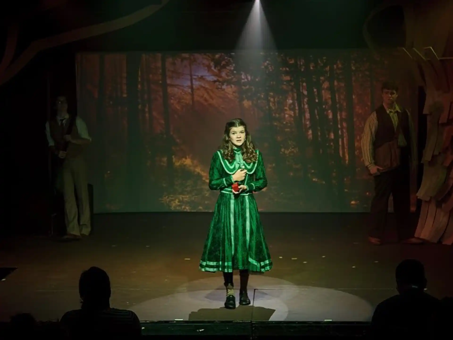 a person in a green dress on a stage with people in the back