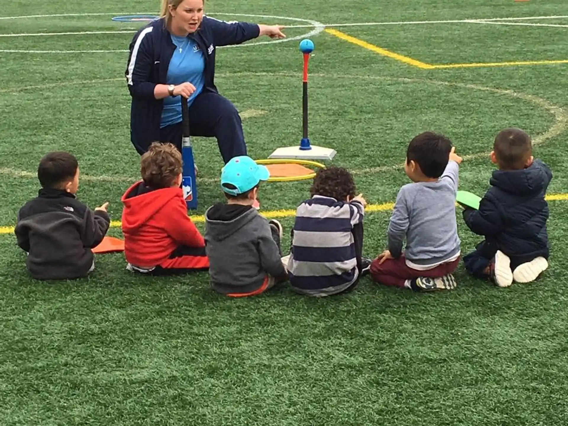 a person and several children sitting on the grass