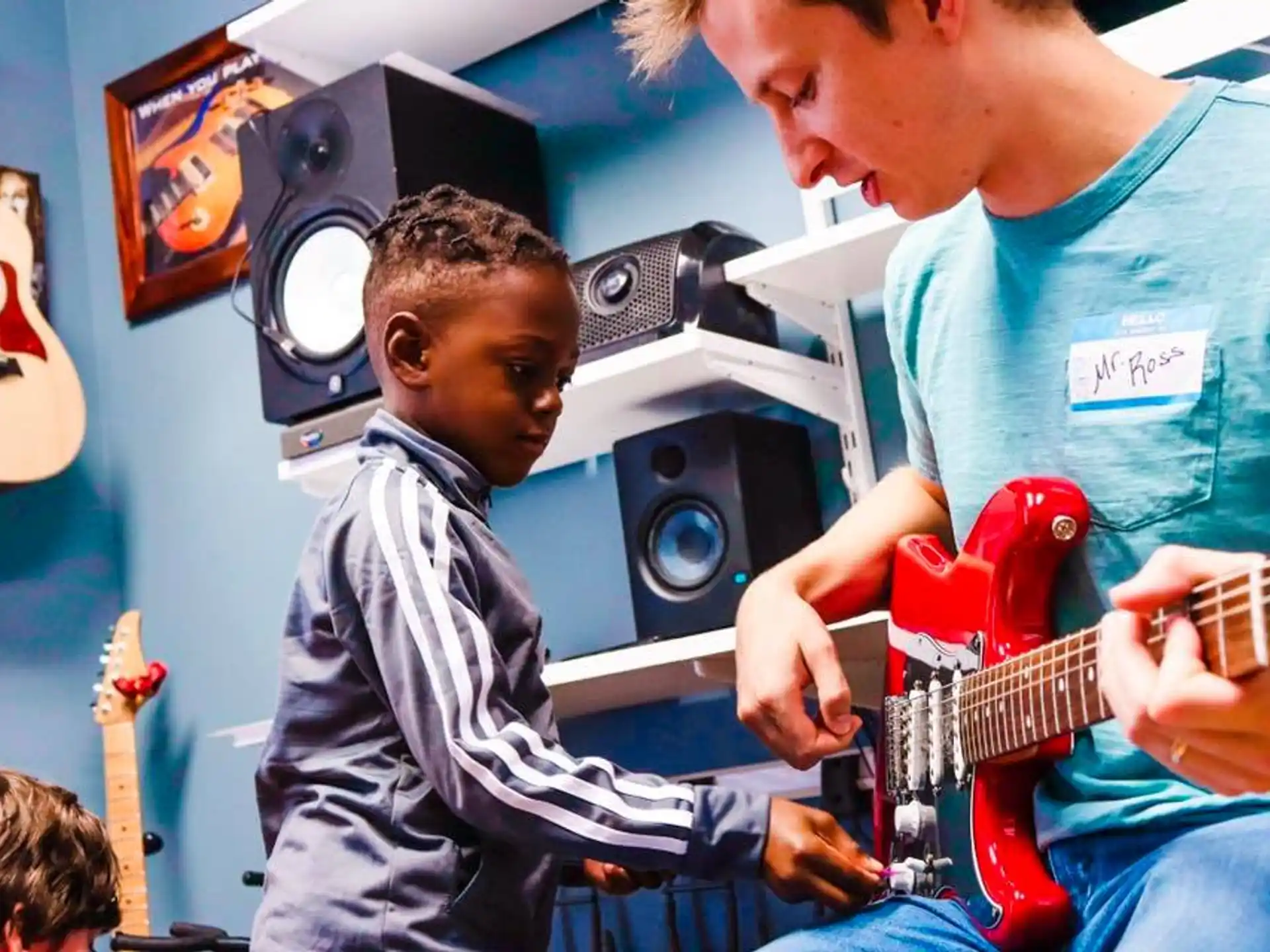 a person playing a guitar next to a boy playing a guitar