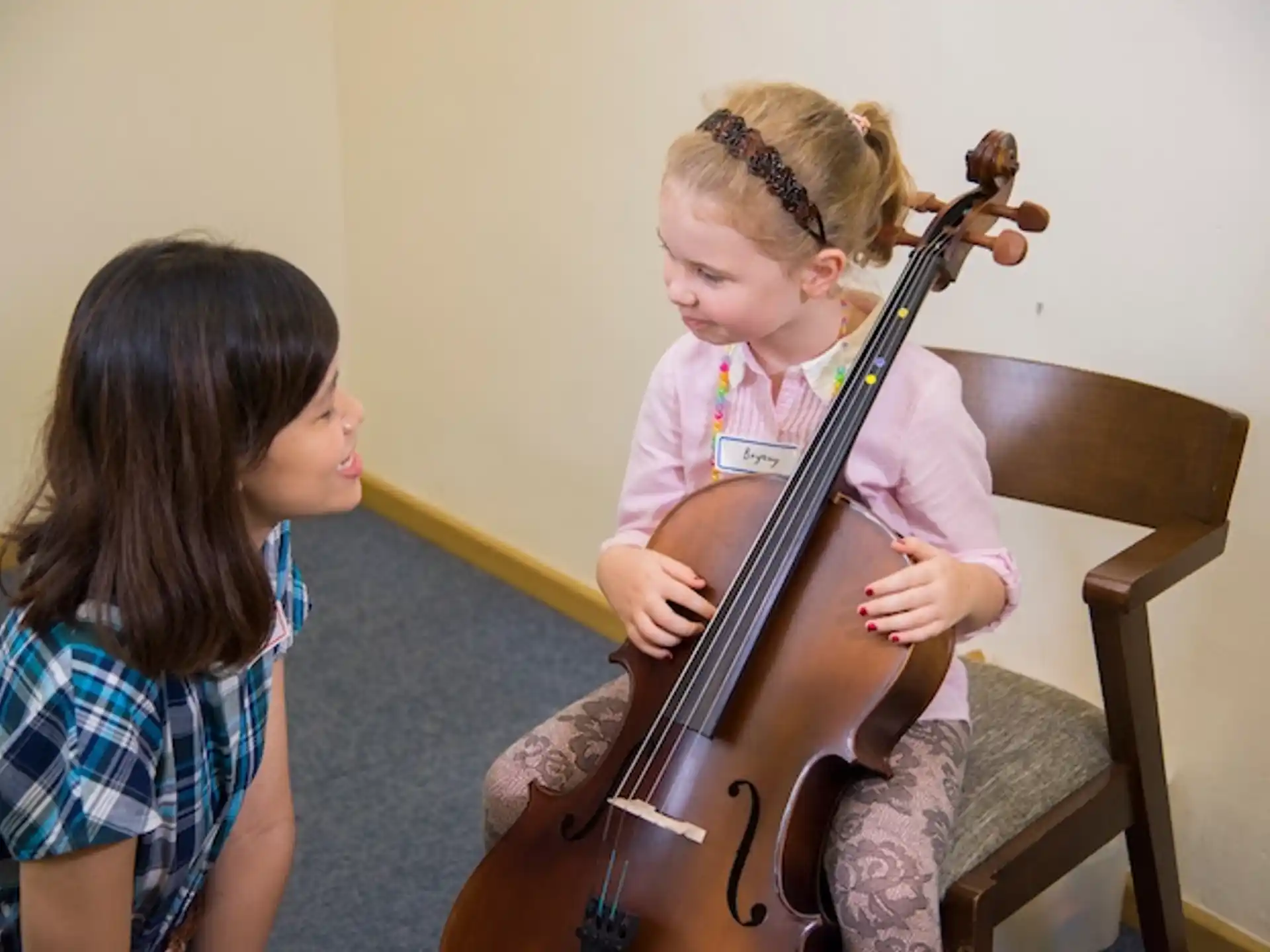 a girl playing a cello next to a girl